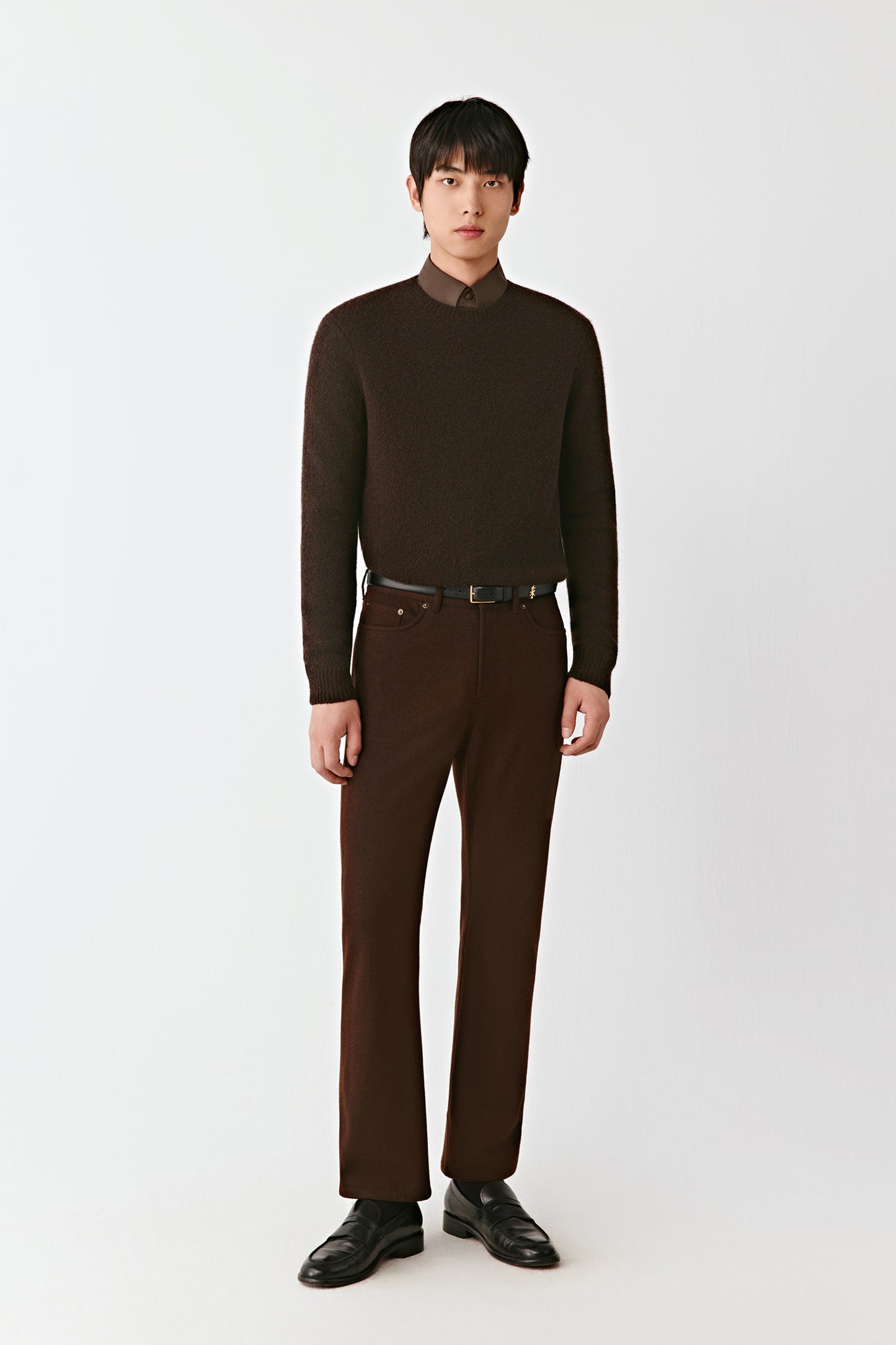 Man wearing a brown turtleneck sweater and pants on a white background