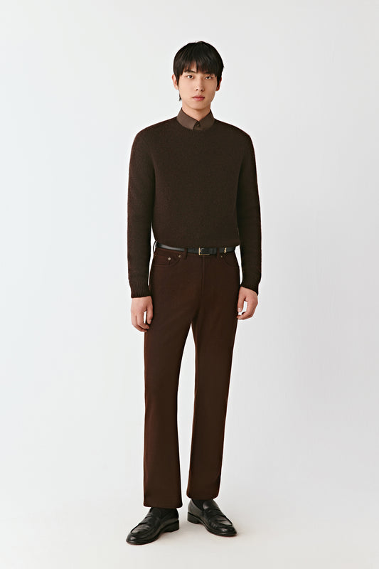 Man wearing a brown turtleneck sweater and pants on a white background