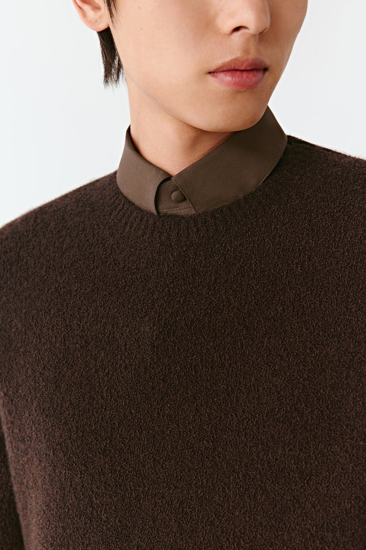 Close-up of a person wearing a brown sweater with a collar.
