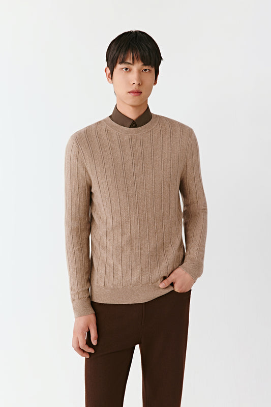 Man wearing a beige sweater and brown pants on a white background