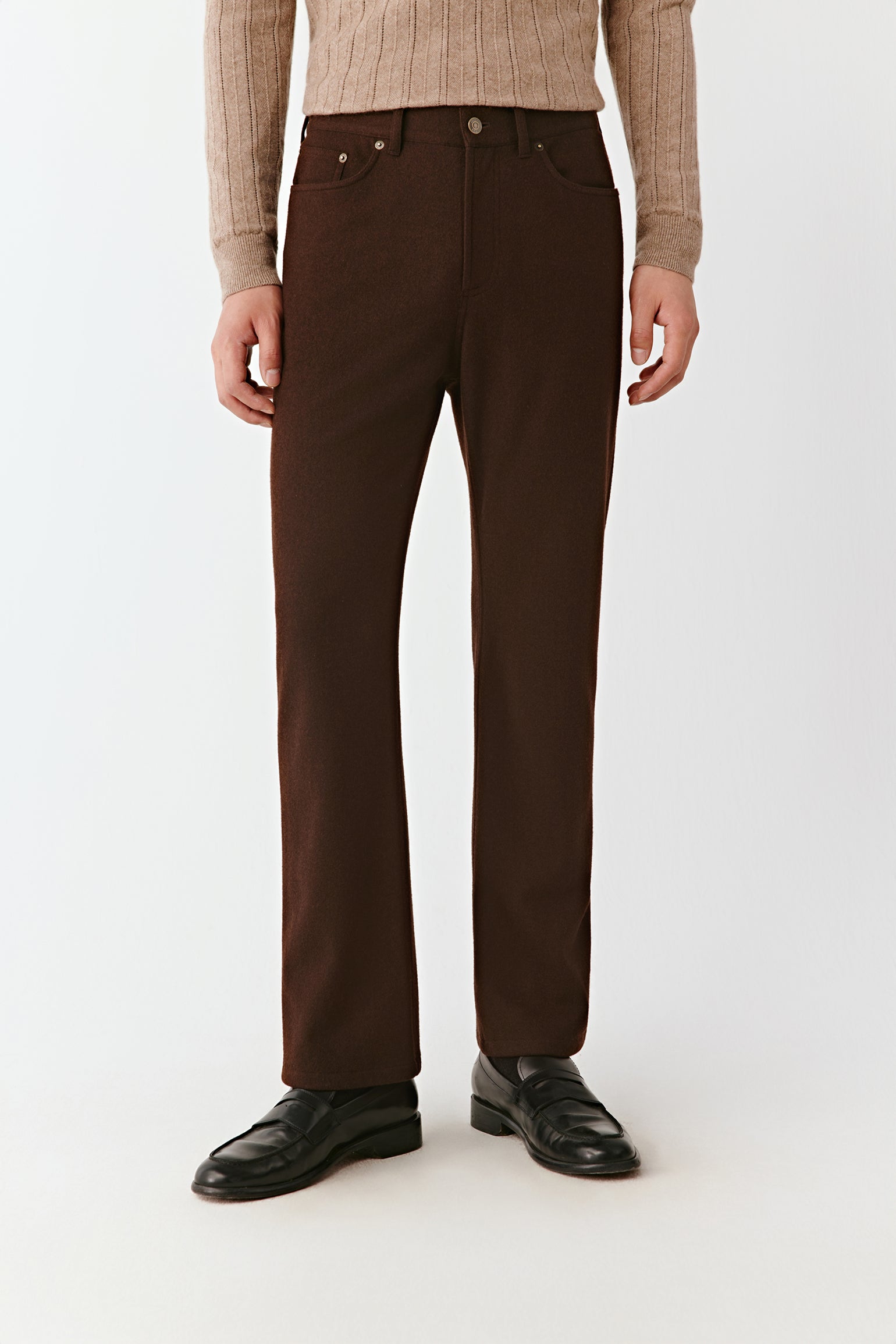 Person wearing brown pants and a beige sweater on a white background