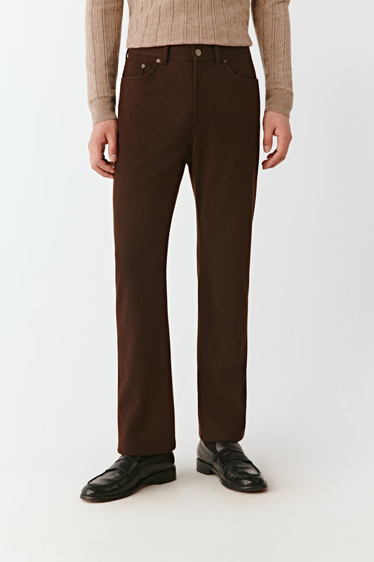 Person wearing brown pants and a beige sweater on a white background