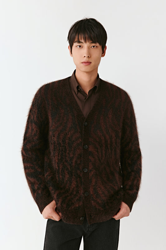 Man wearing a brown patterned cardigan over a shirt on a white background