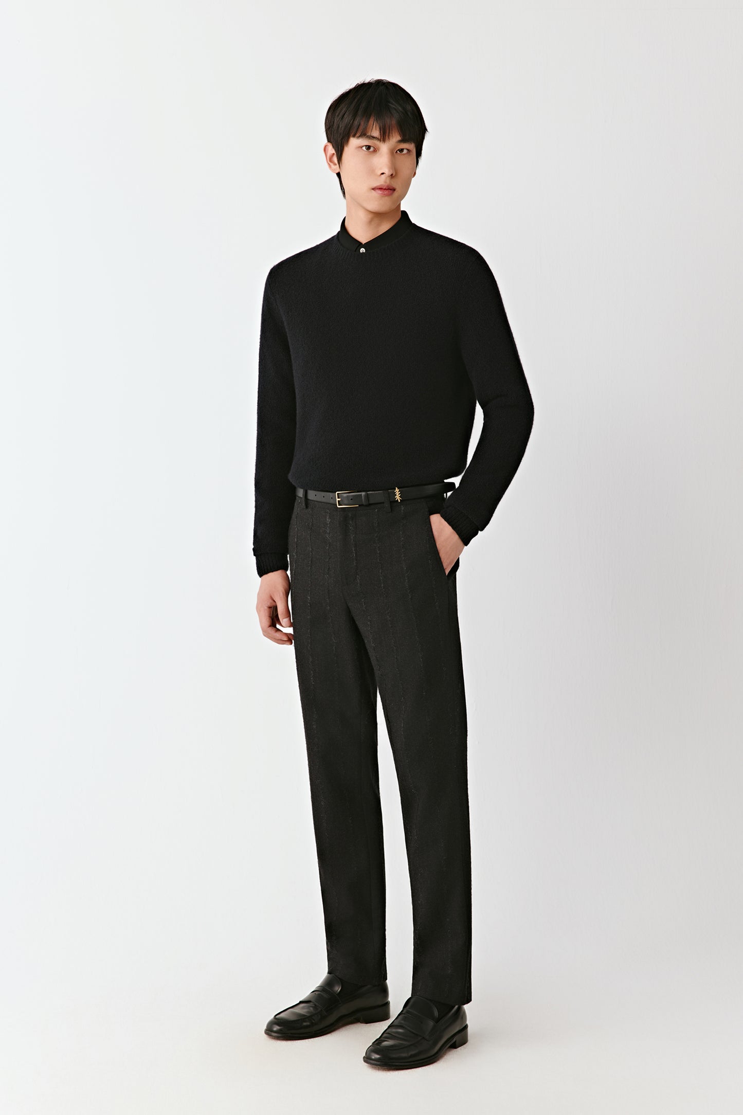 Full-length front view of straight-leg trousers in a dark pinstripe wool-blend, styled with a black knit top.