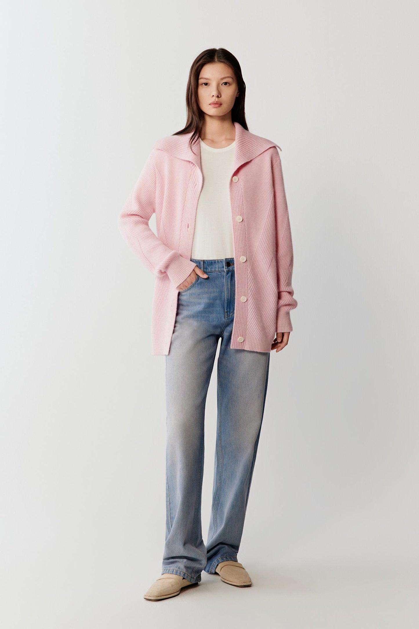 Full-length front view showing the cardigan paired with blue jeans and a white top. The soft pink melange shade creates subtle tonal variation across the knit surface.