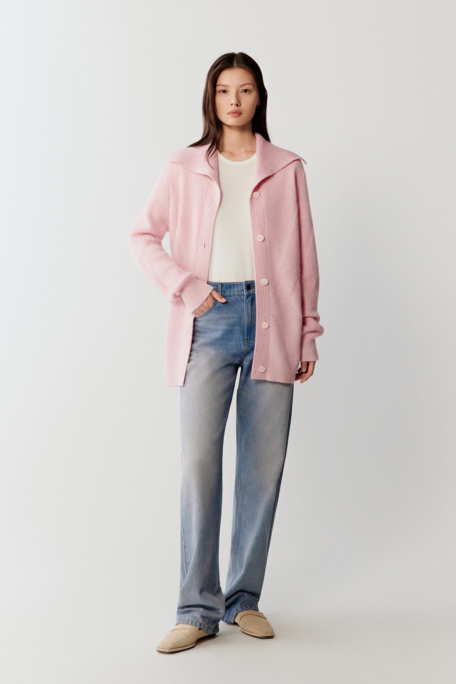 Full-length front view showing the cardigan paired with blue jeans and a white top. The soft pink melange shade creates subtle tonal variation across the knit surface.