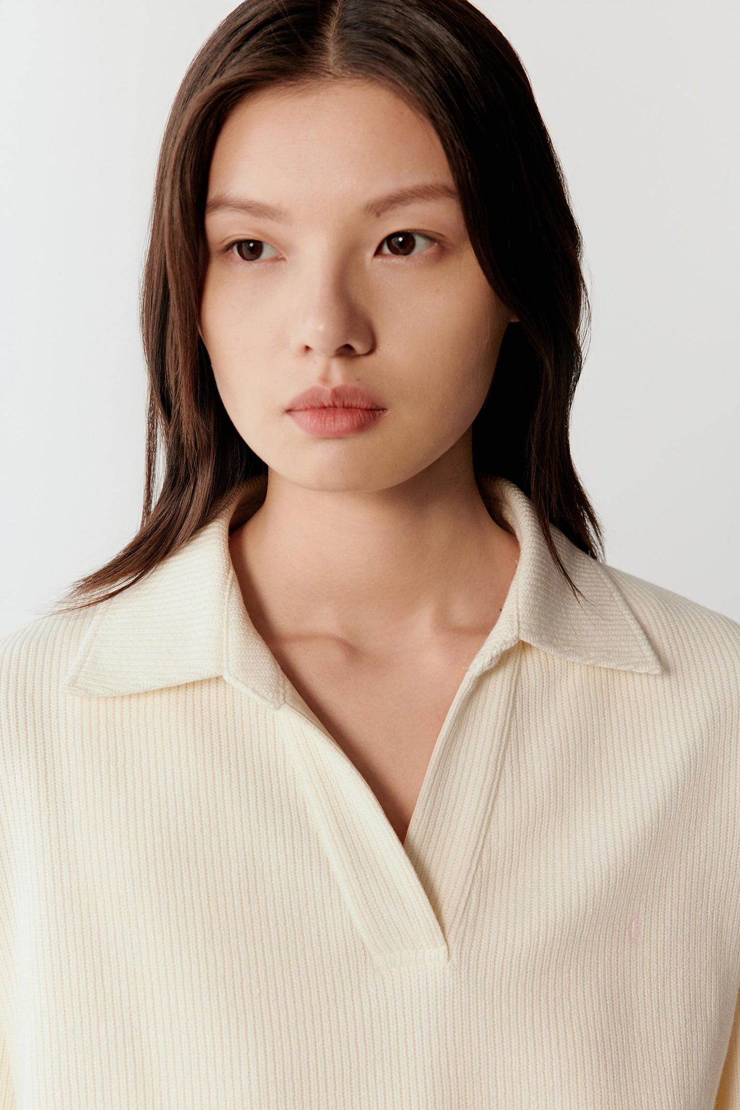 Close-up portrait focusing on the open collar and upper chest area, highlighting the soft ribbed knit texture.