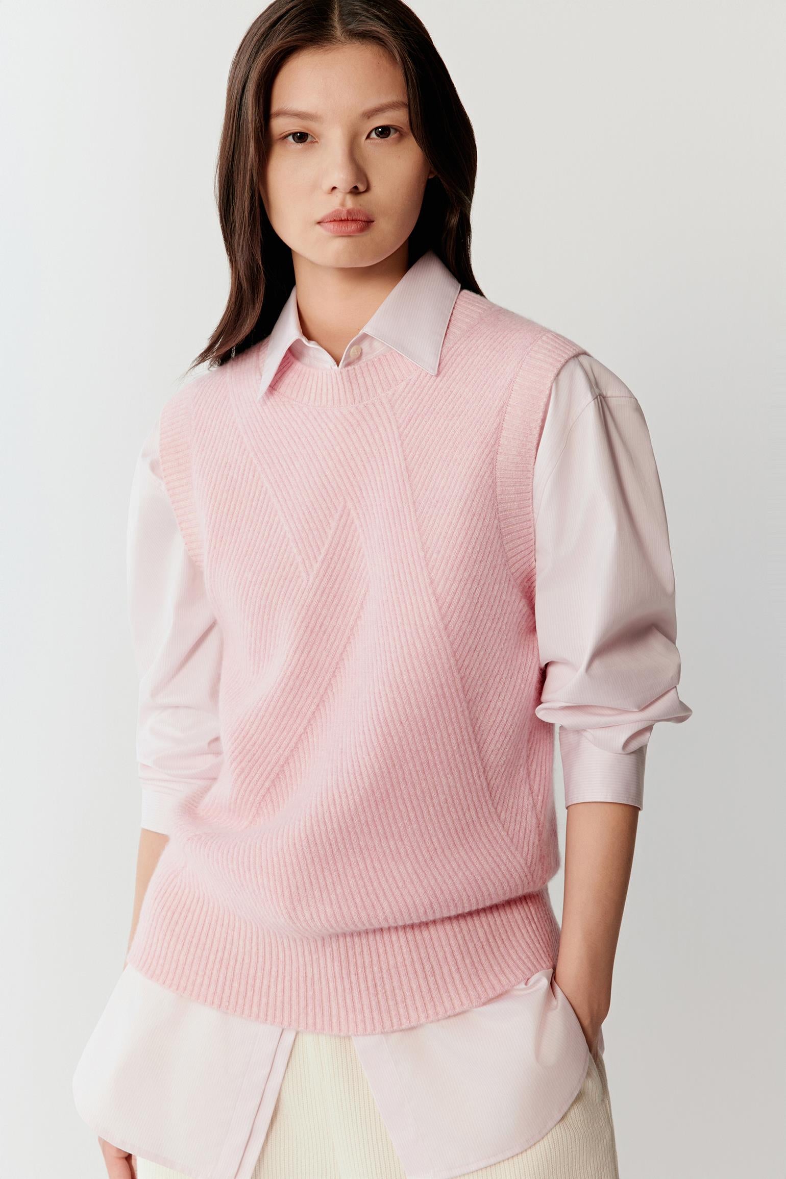Female model wearing a pink melange knit pullover layered over a pink shirt.
