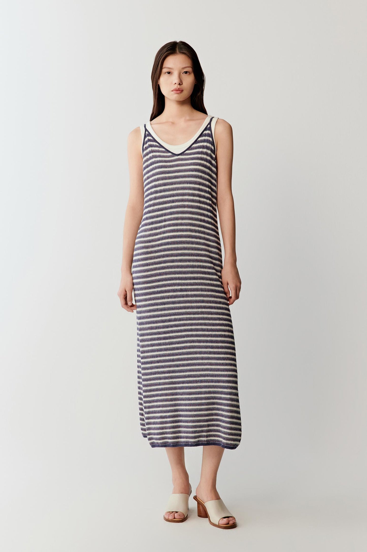 Mid-length front view focusing on the vertical fall of the dress, emphasizing the softly curved neckline, fine straps and continuous striped pattern with fluid drape