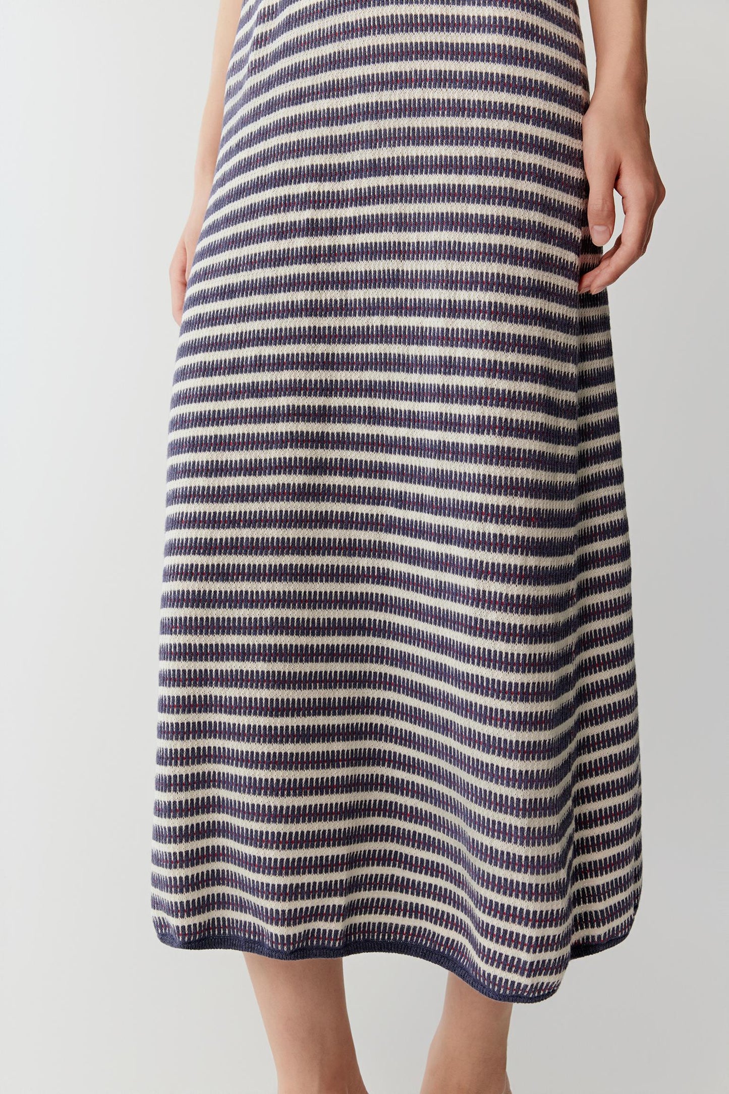 Close-up of the lower skirt area showing the lightweight knitted texture, stripe alignment and natural fluidity of the linen and silk yarn construction