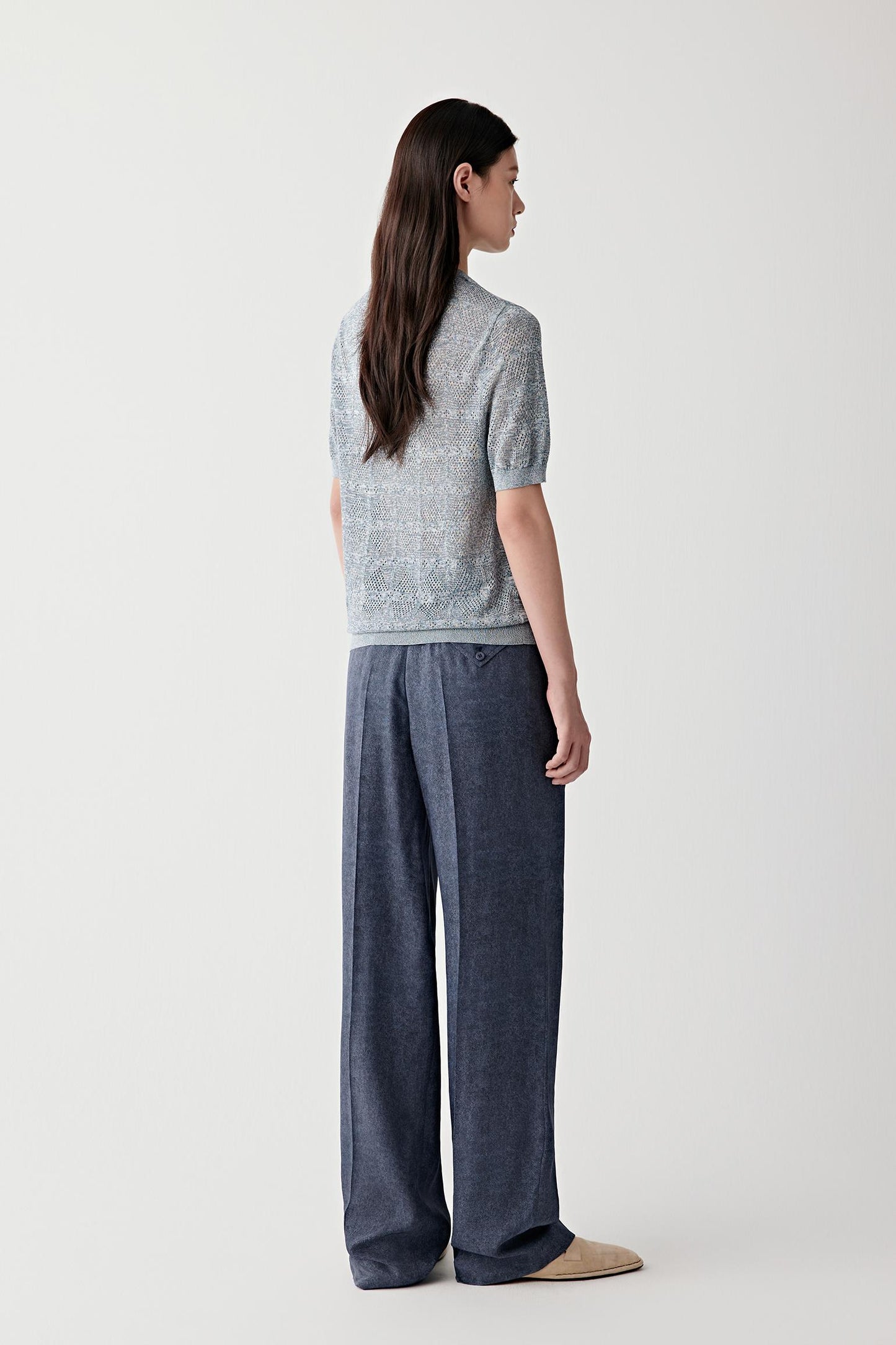 Full-length side or three-quarter view highlighting the straight silhouette, soft movement and open knit construction, with the blue and white melange yarn creating subtle tonal depth