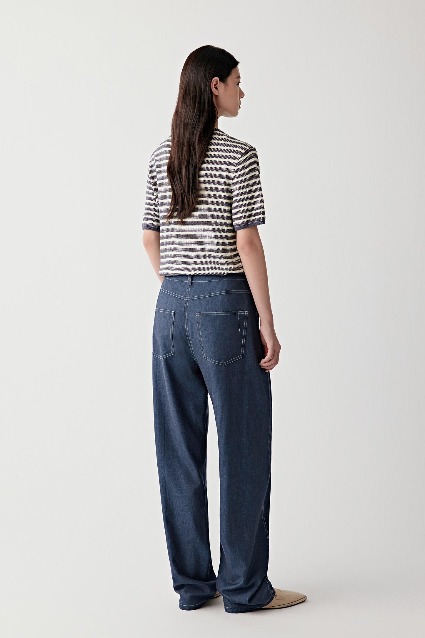 Three-quarter back or side view highlighting the continuous striped construction, soft drape and lightweight structure, with the knit adapting fluidly to movement