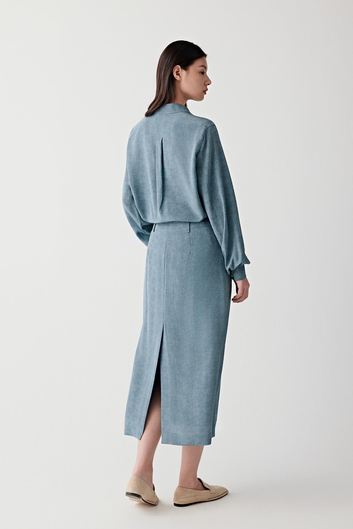 Full-length back view highlighting the drape through the back and sleeves, showing the fluid movement and lightweight construction of silk crêpe de Chine with clean vertical lines
