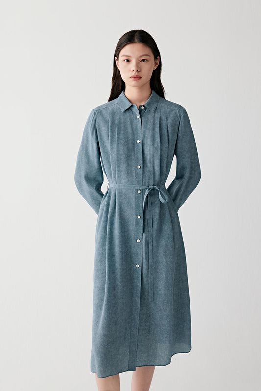 Mid-length front view emphasizing the self-tie belt, softly gathered waist and fluid drape of the skirt, with the indigo blue tone revealing tonal variation and a matte silk surface