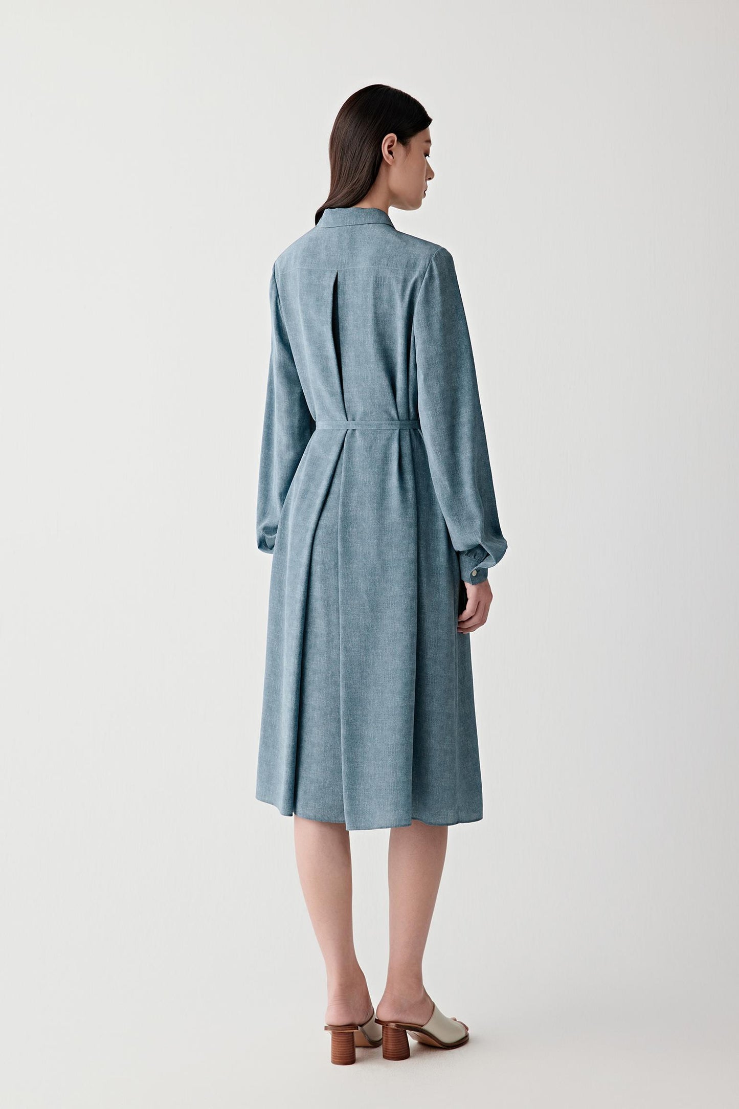 Full-length back or three-quarter rear view showing the elongated silhouette, soft pleating and fluid movement through the skirt and back construction