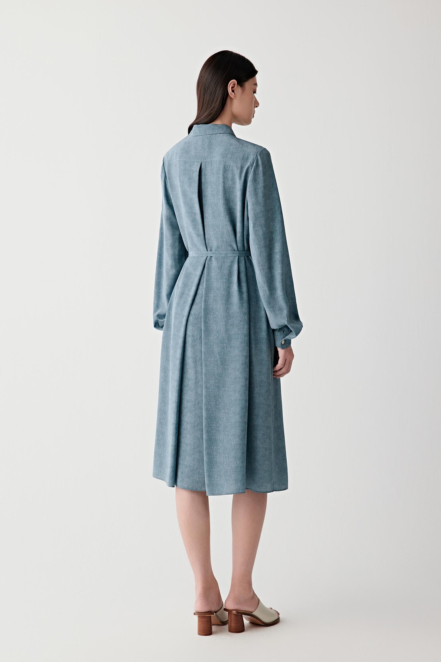 Full-length back or three-quarter rear view showing the elongated silhouette, soft pleating and fluid movement through the skirt and back construction