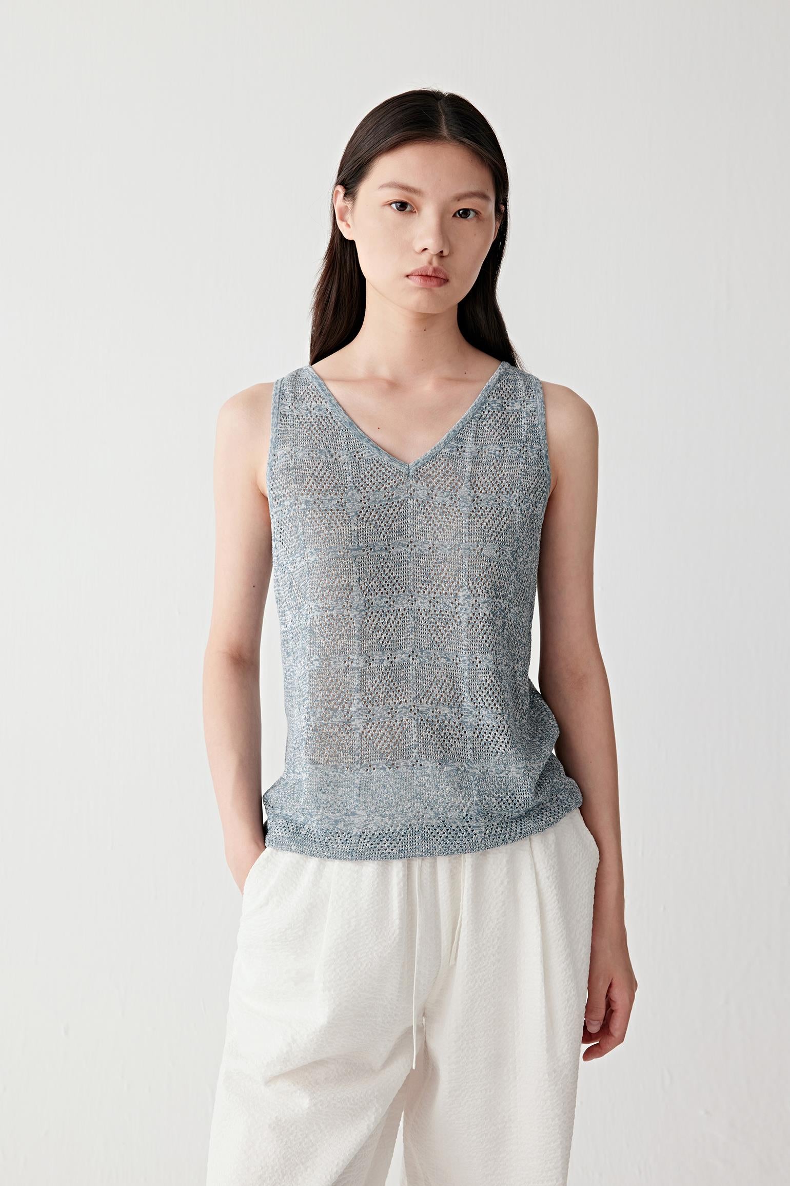 Front view of a woman wearing a grey cotton and silk knitted vest with a sleeveless cut and V neckline, highlighting the openwork knit structure, lightweight feel and softly textured melange surface