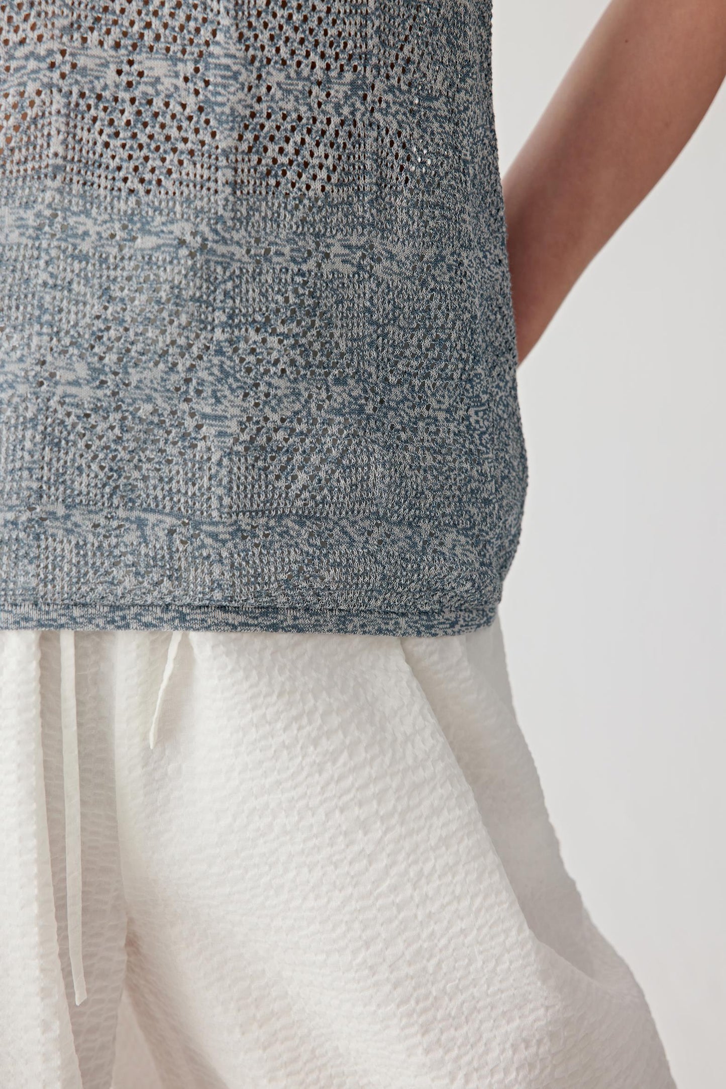 Close-up of side seam and hem showing the ribbed trim, knit texture and subtle transparency created by the openwork cotton and silk construction