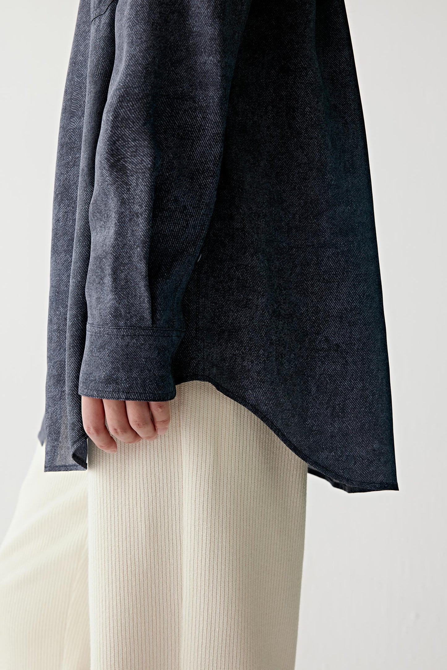 Close-up of sleeve and hem showing visible stitching, lightweight drape and the smooth fluid texture characteristic of silk twill construction