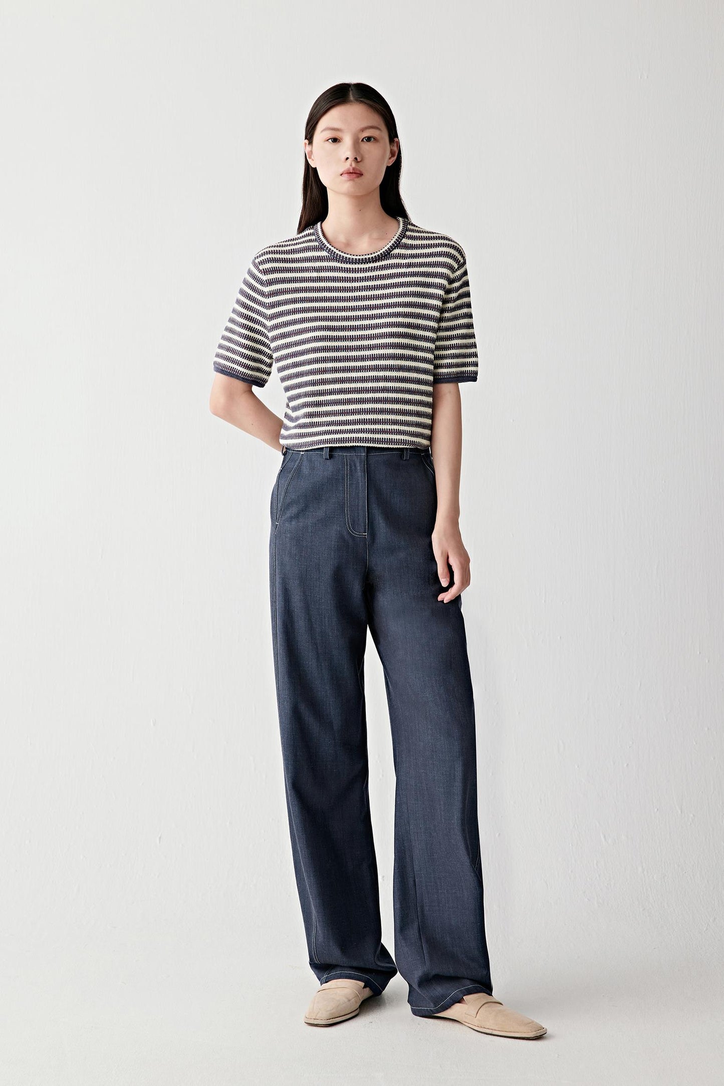 Full-length front view showing the striped pullover paired with dark denim trousers, emphasizing the relaxed fit, short sleeves and naturally fluid movement of the knit fabric