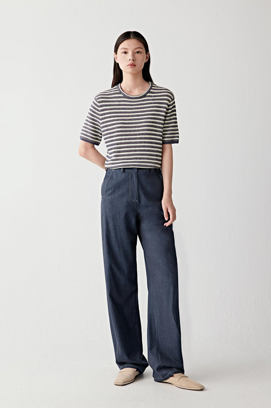 Full-length front view showing the striped pullover paired with dark denim trousers, emphasizing the relaxed fit, short sleeves and naturally fluid movement of the knit fabric
