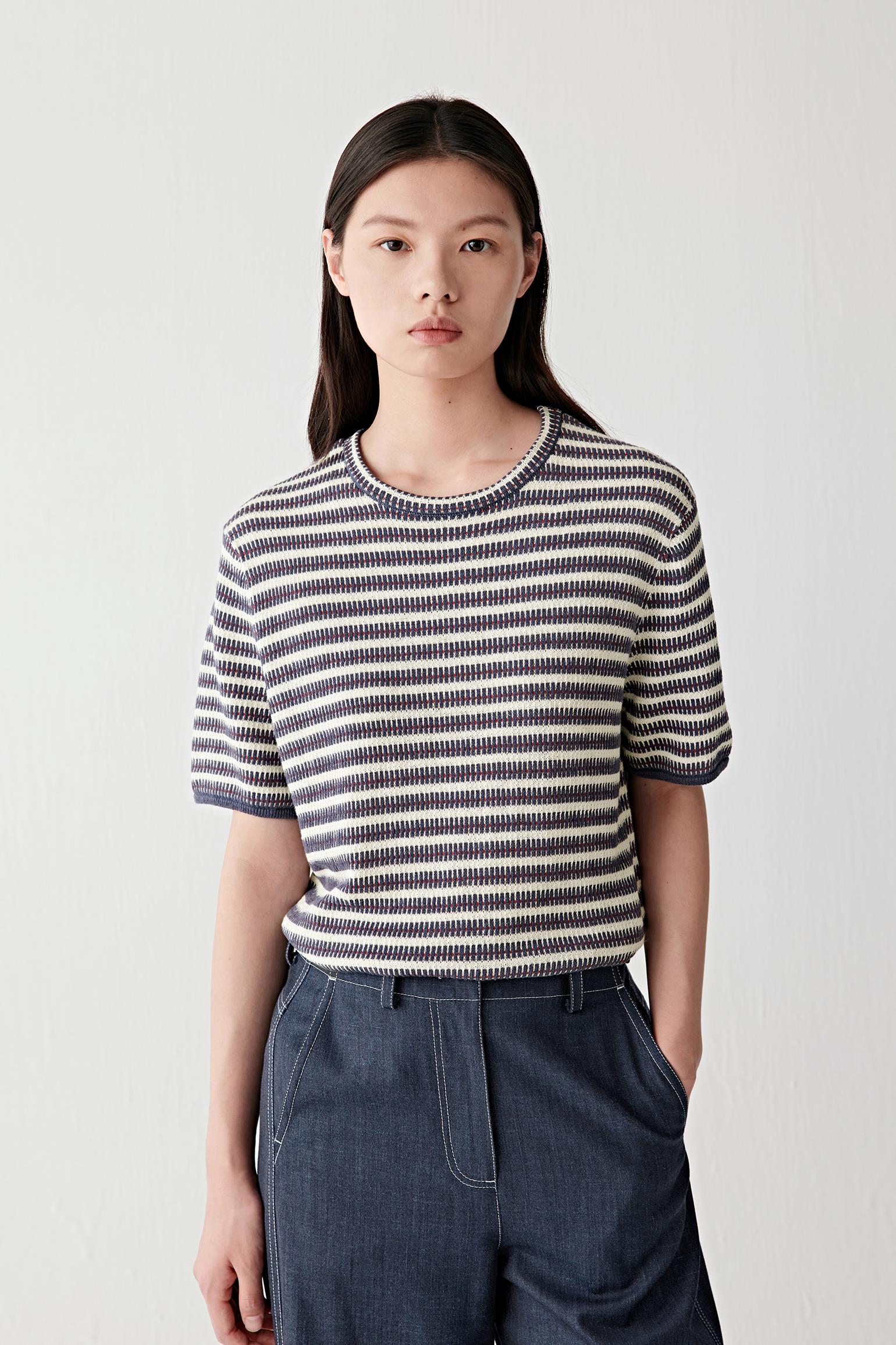 Front view of a woman wearing a knitted linen and silk pullover with alternating navy, off-white and subtle red stripes, highlighting the lightweight knit texture, relaxed silhouette and fluid drape