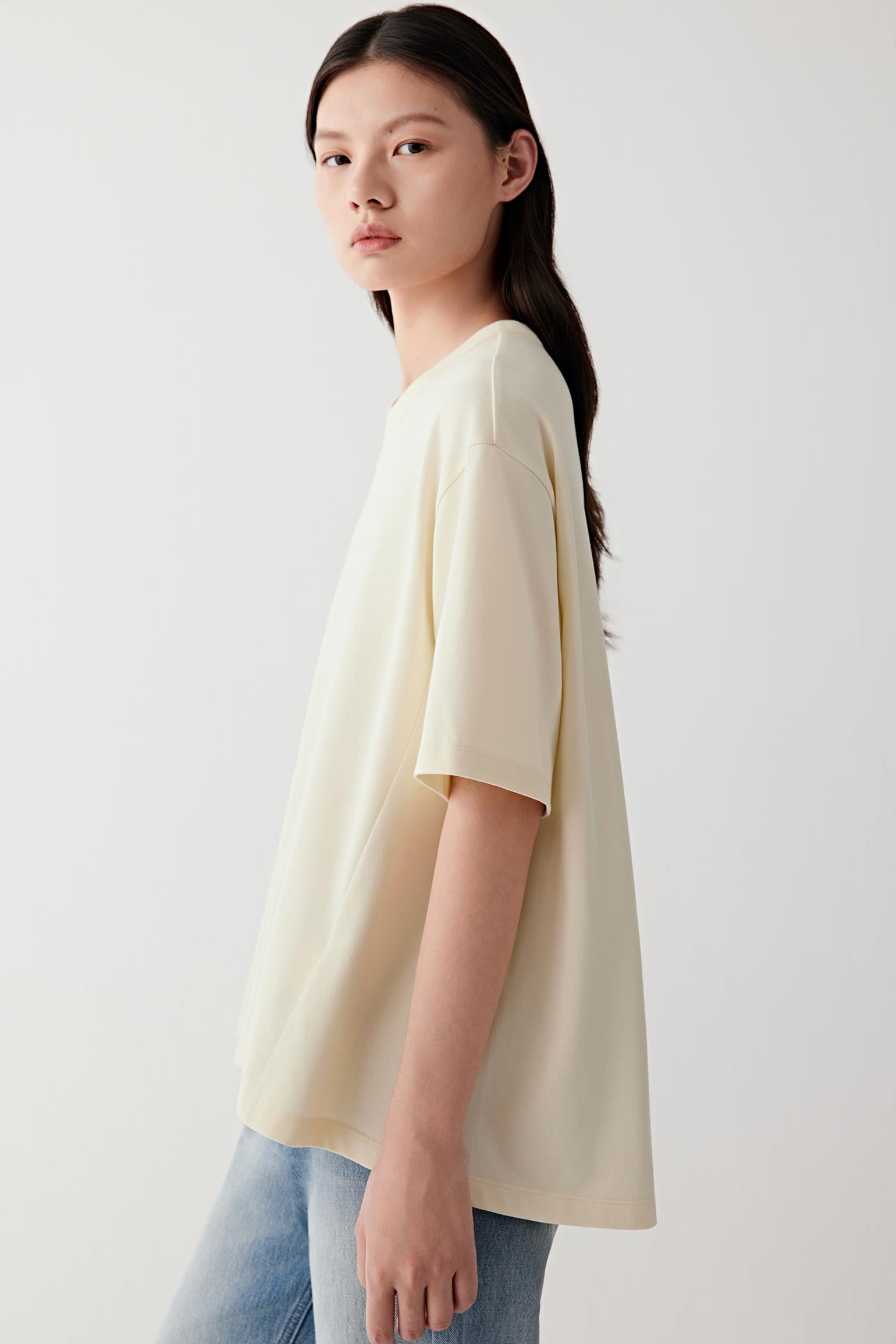 Three-quarter view showing the relaxed fit through the body and sleeves. The image reveals the smooth matte surface of the jersey fabric and the balanced proportions of the design.