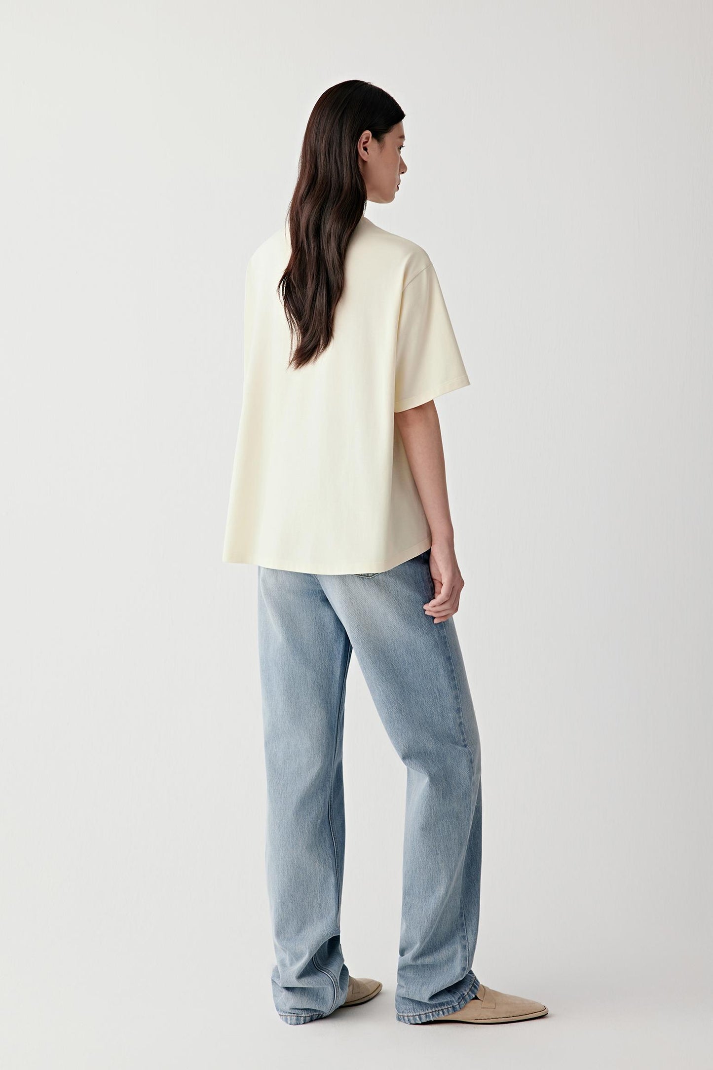 Side view highlighting the straight silhouette, short sleeves and clean side seam construction. The lightweight cotton jersey falls softly from the shoulders, creating a fluid and natural shape.