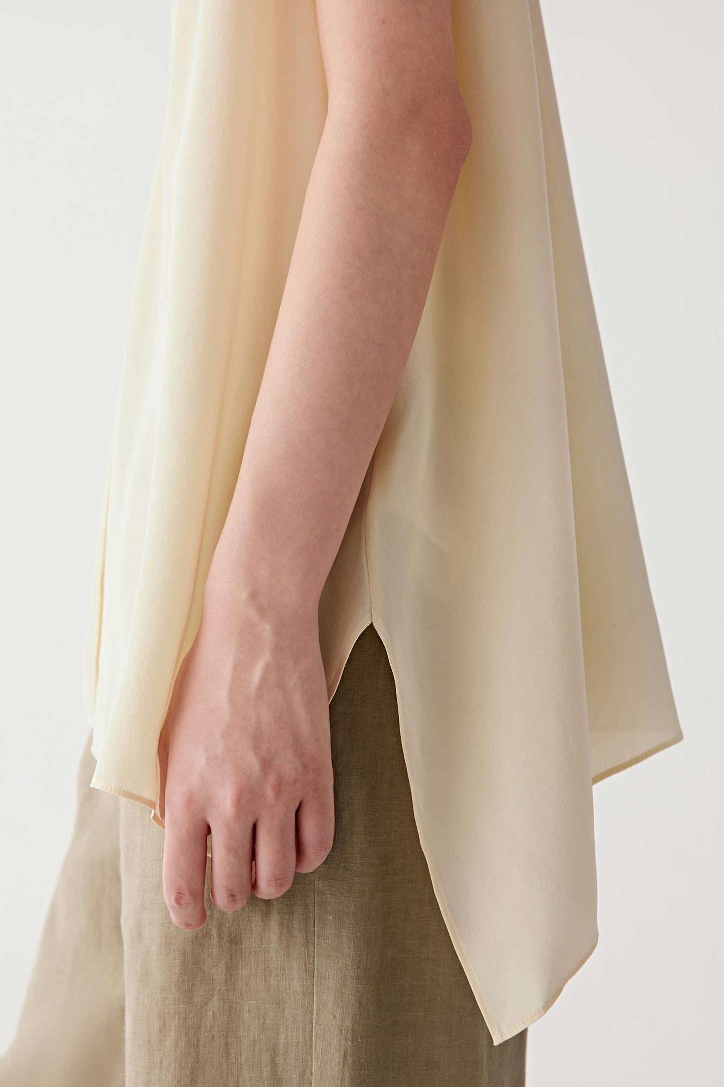 Close-up of the side hem and lower section of the blouse, showing the lightweight drape, fluid movement and matte finish of the silk fabric. The image reveals the clean finishing and subtle texture of the material.