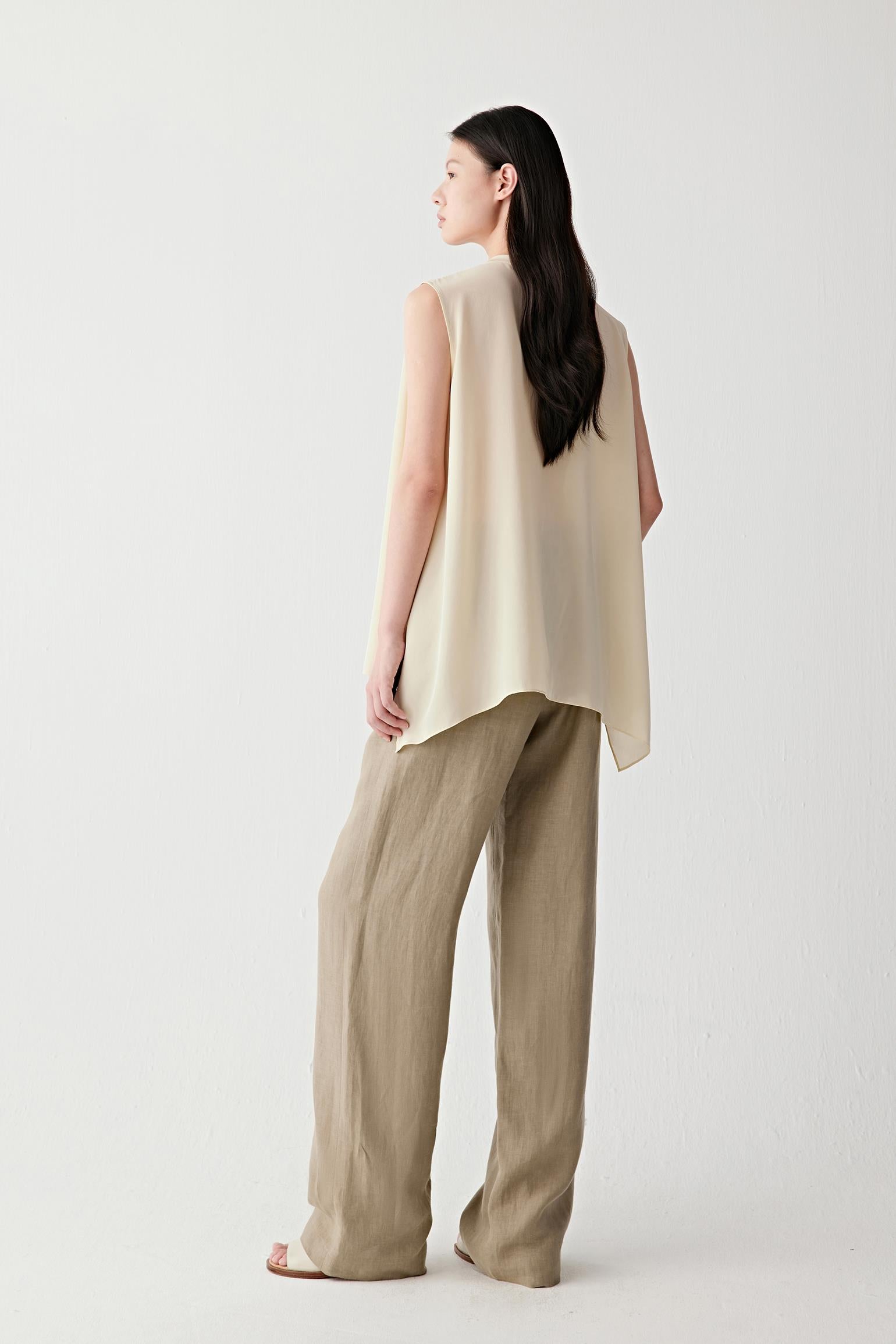Side view highlighting the fluid shape of the blouse and the way the lightweight silk follows the body. The image reveals the soft volume created by the gathered neckline and the relaxed fit through the torso.