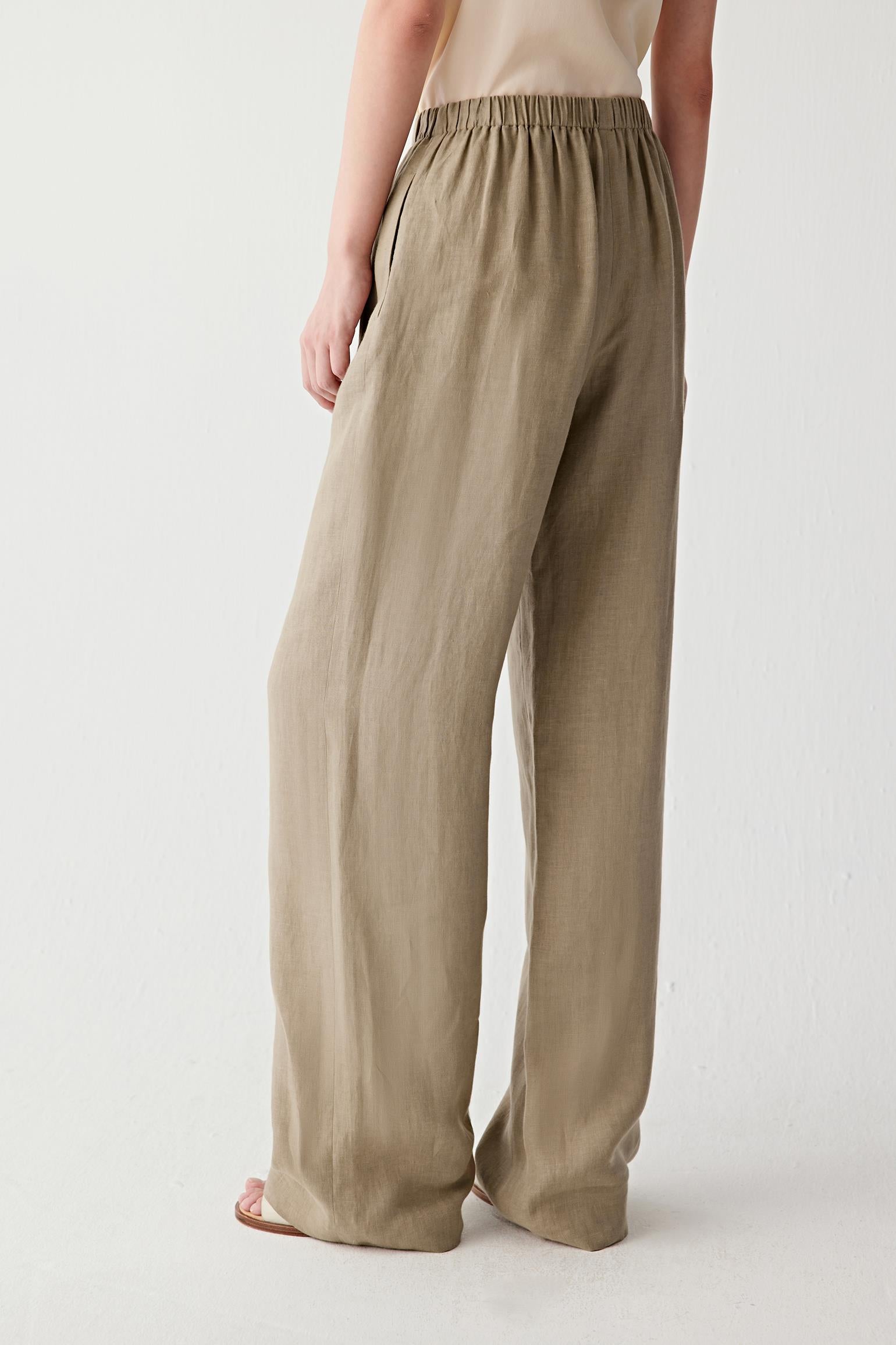 Angled rear view highlighting the volume and drape of the trousers. The image reveals the relaxed structure of the garment and the characteristic texture of the linen weave.