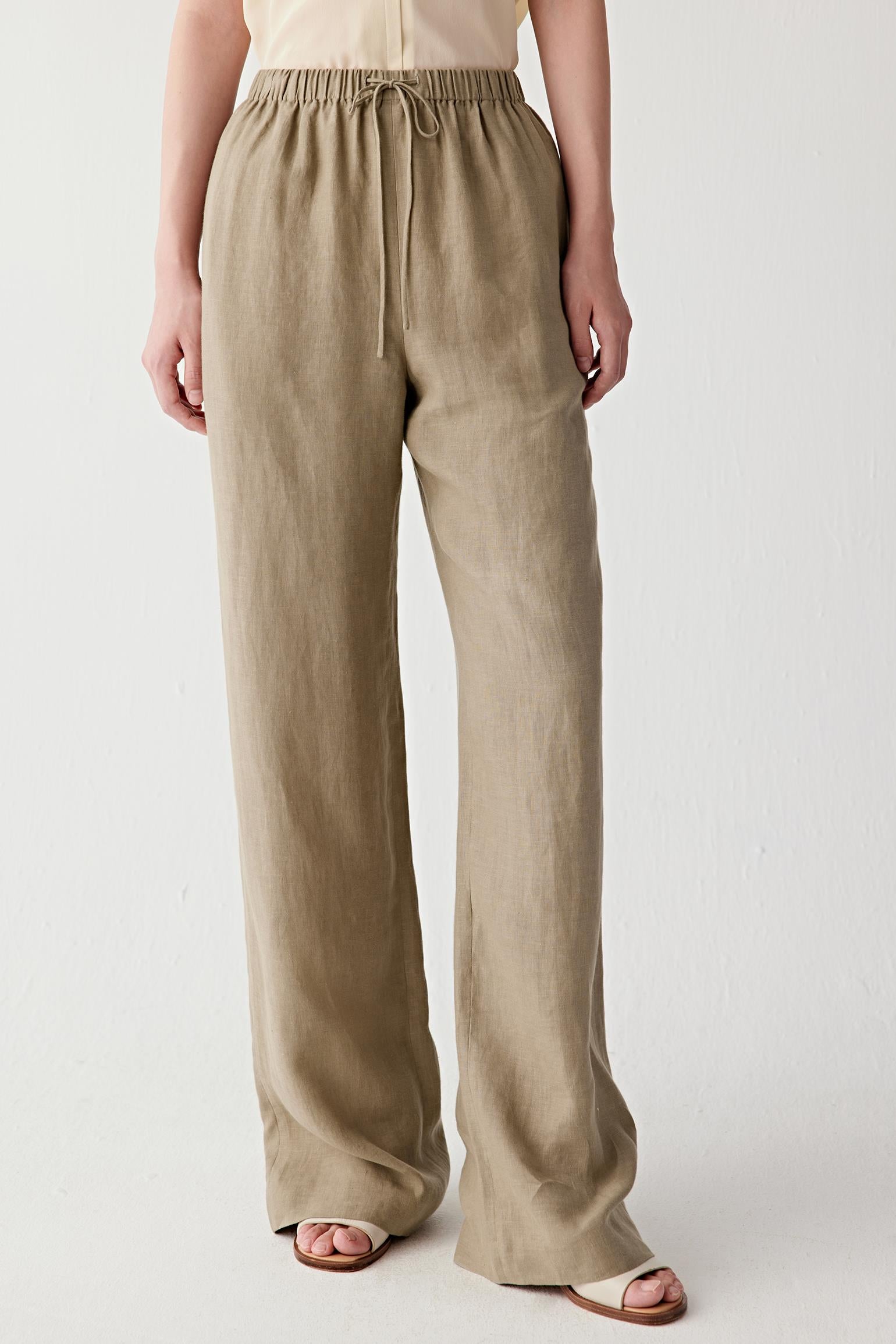 Three-quarter view focusing on the clean proportions of the trousers and the fluid drape of the linen fabric. The image emphasizes the relaxed fit, lightweight construction and effortless movement of the straight-leg silhouette.