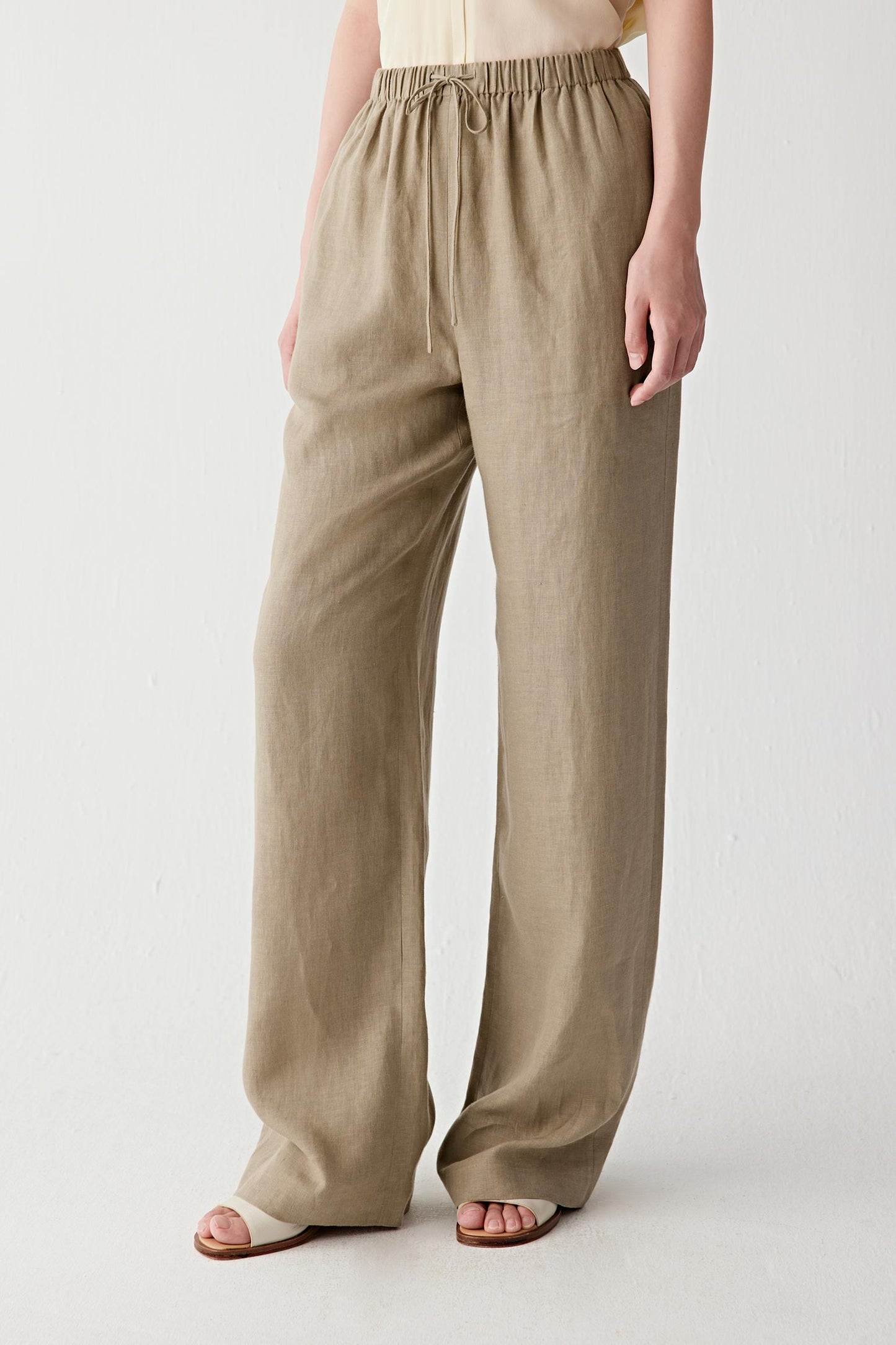 Side view showing the straight cut and natural fall of the linen fabric from the elasticated waistband. The lightweight weave creates soft movement while preserving the clean line of the leg.