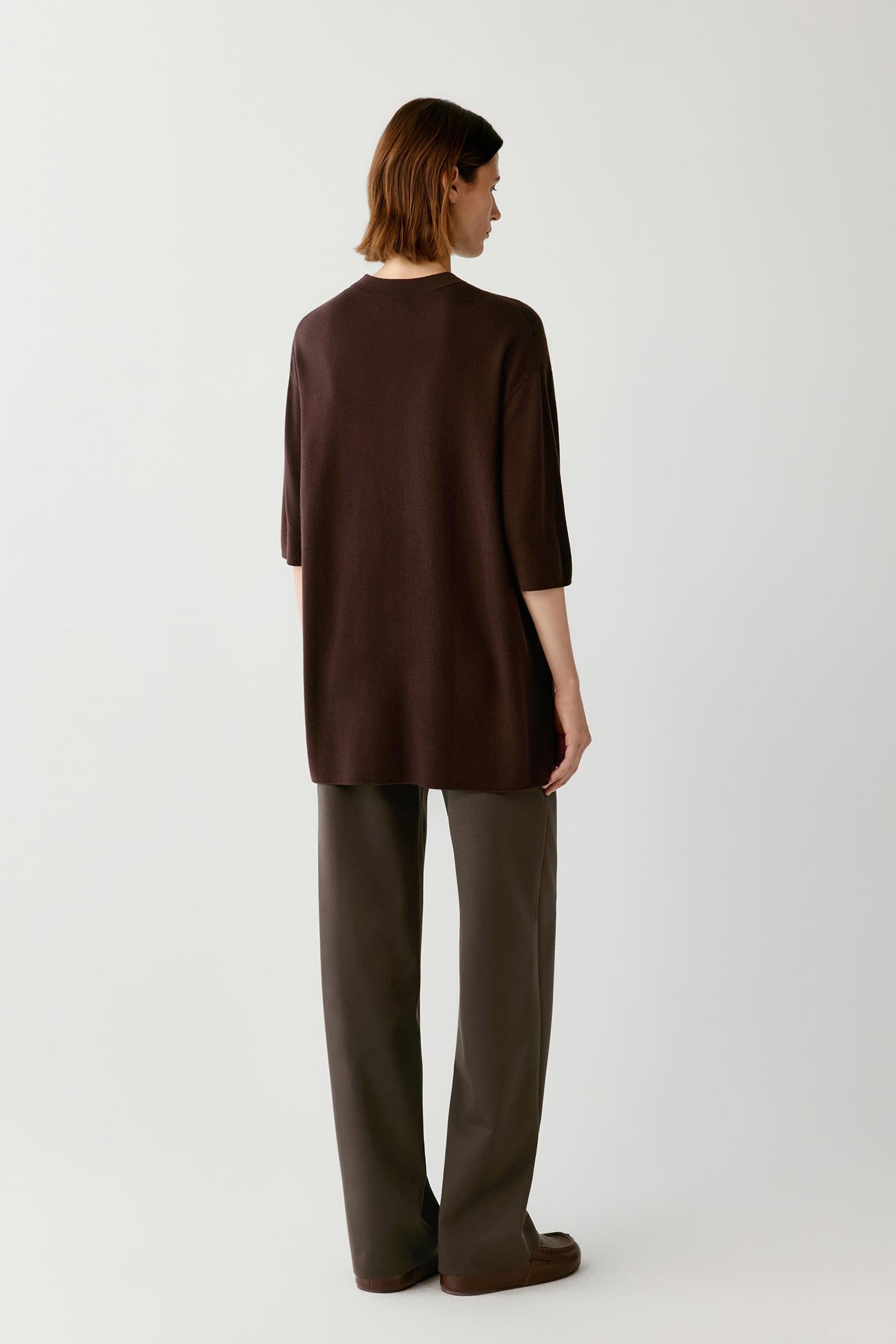 A model shown from the back wearing a dark brown short-sleeve top and matching dark brown wide-leg trousers against a light gray studio background.