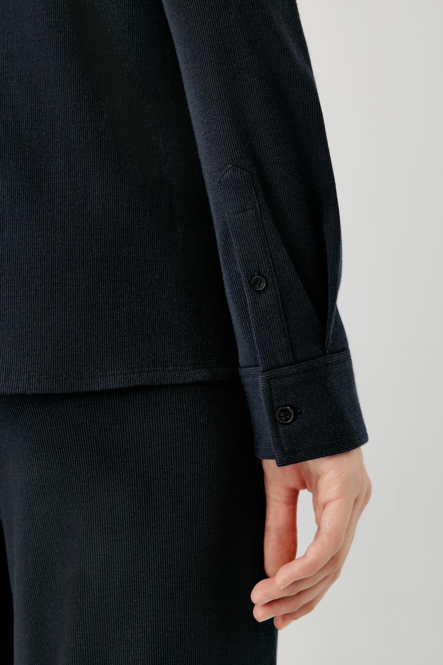Close-up of the buttoned cuff and textured fabric of a navy shirt.