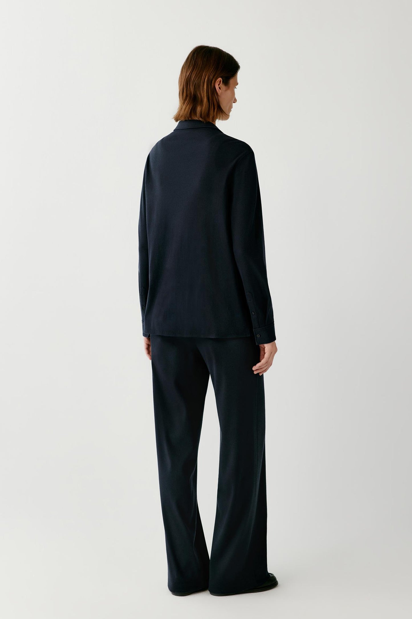 Back view of a woman wearing a navy shirt and matching wide-leg trousers.