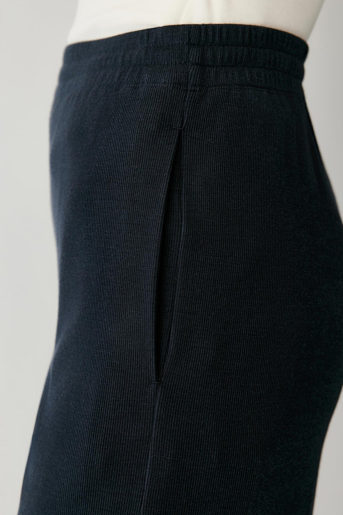 Close-up of dark navy corduroy pants on a mannequin, showing the ribbed waistband and fabric texture.