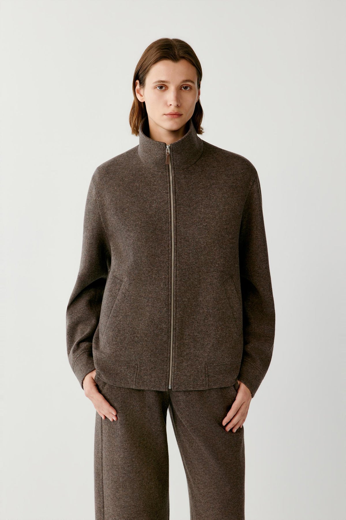 Front view highlighting the stand collar, two-way zip fastening and straight silhouette of the brown melange blouson.