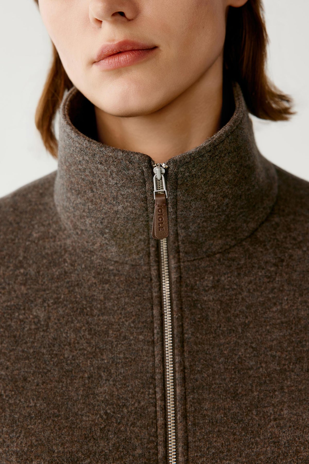 Close-up highlighting the stand collar, front zip fastening and brown melange jersey texture.