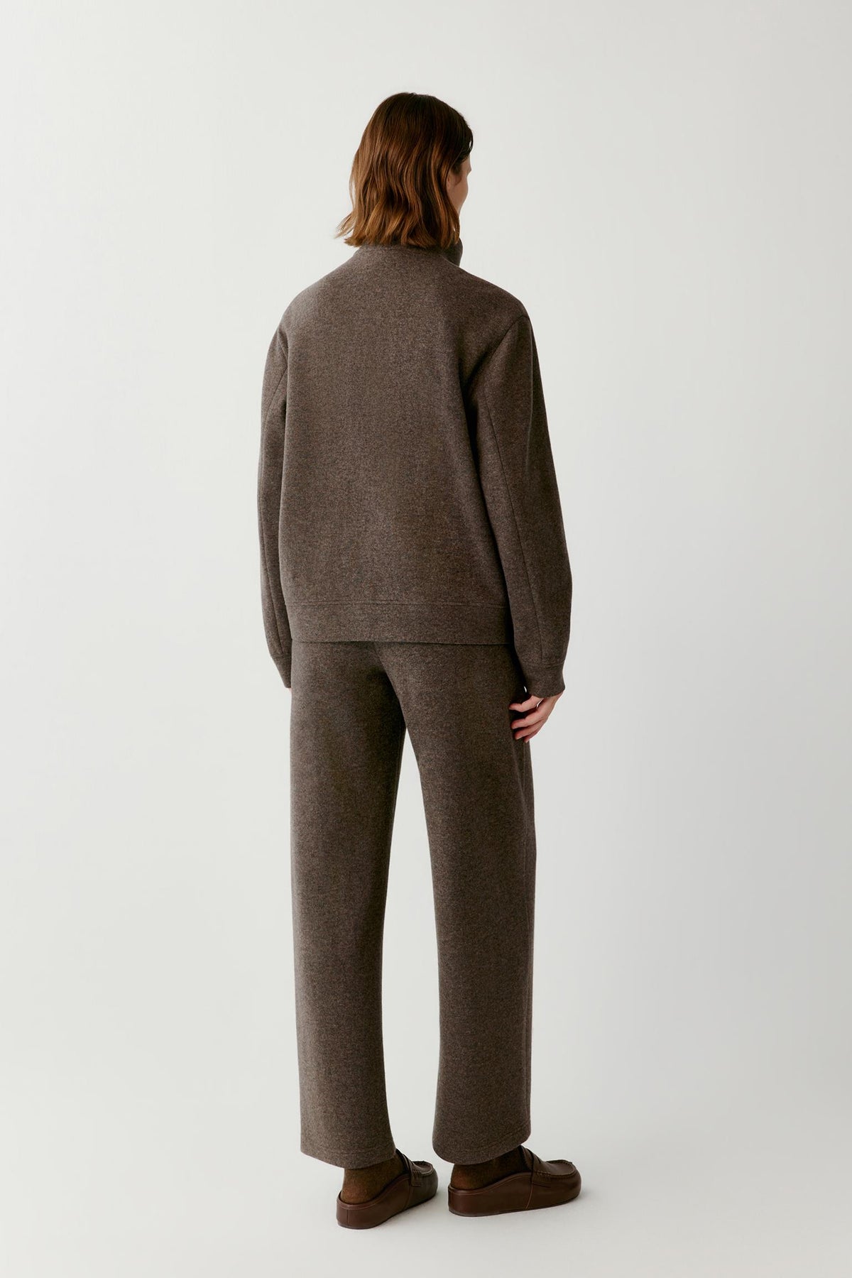 Back view of a woman wearing the brown melange wool and cashmere jersey blouson, showing the straight silhouette and long sleeves.