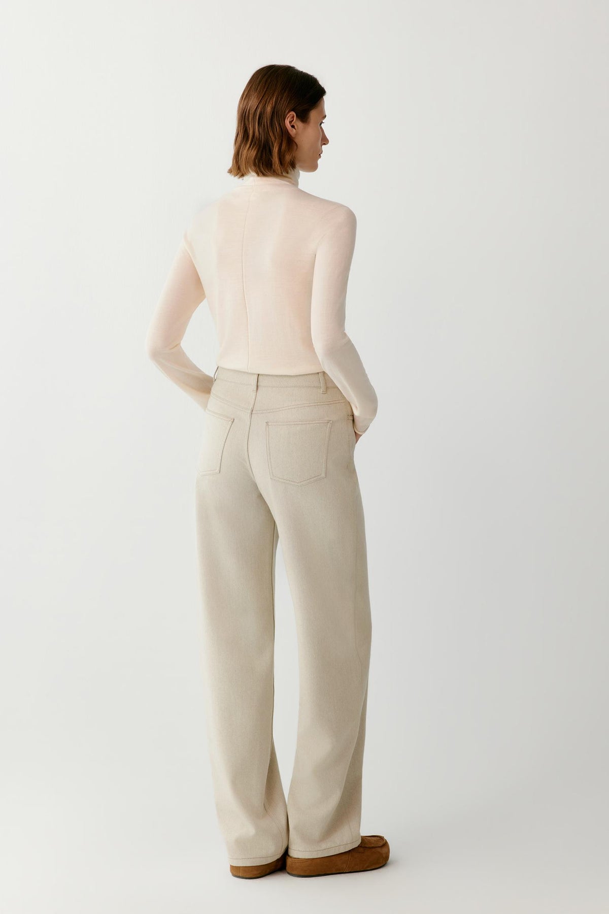Back view of a woman wearing the cream wool and cashmere pullover, showing the turtleneck and straight silhouette.