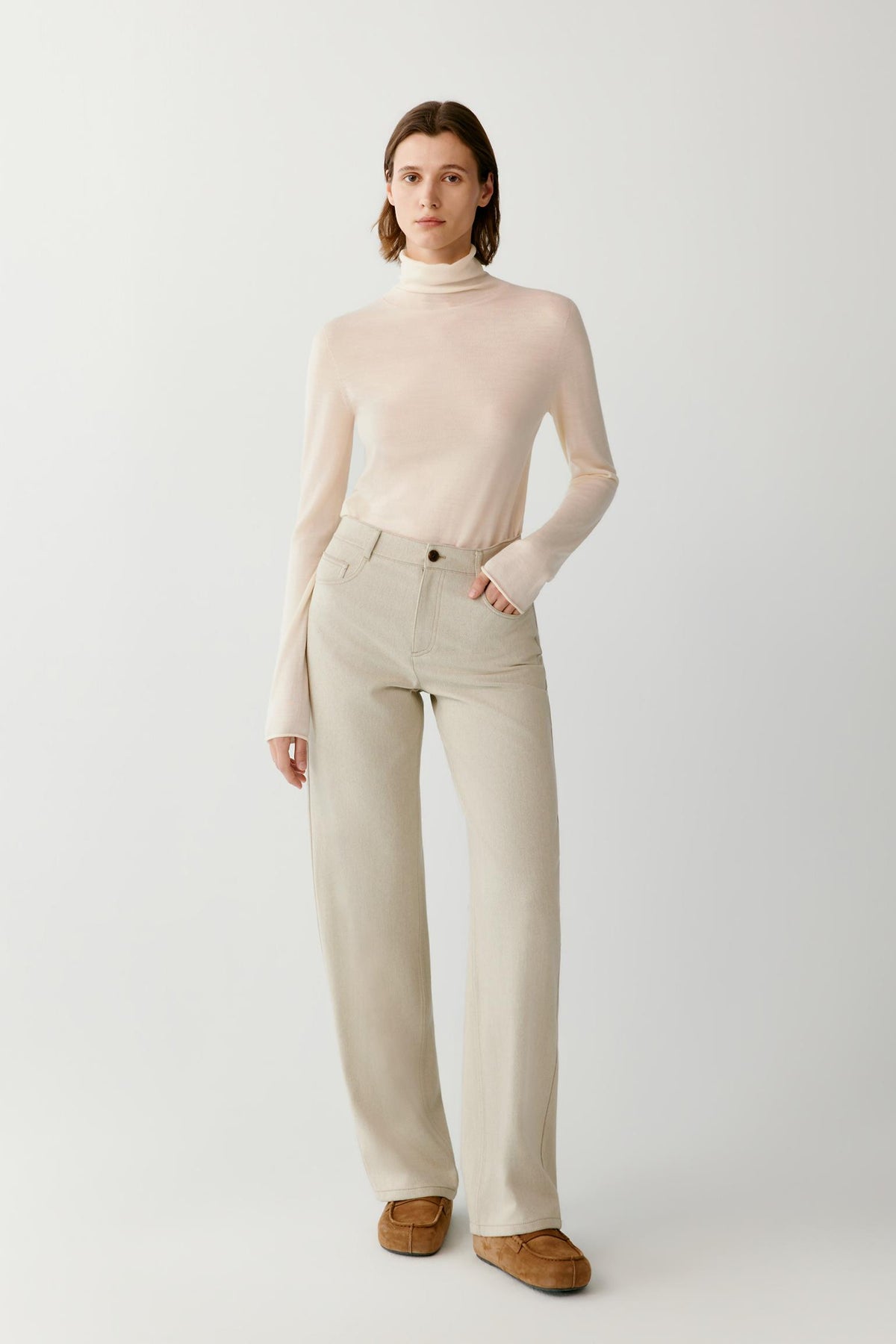Front view of a woman wearing a cream wool and cashmere pullover, showing the turtleneck, long sleeves and straight silhouette.