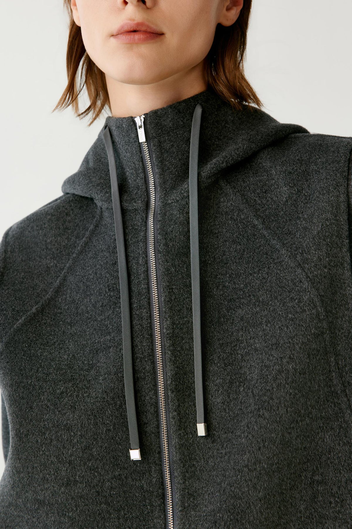 Close-up highlighting the adjustable drawstring hood, zip fastening and dark grey melange texture.