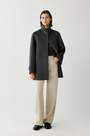 Front full-length view of a woman wearing the dark grey melange wool and cashmere coat, highlighting the high stand collar and straight silhouette.