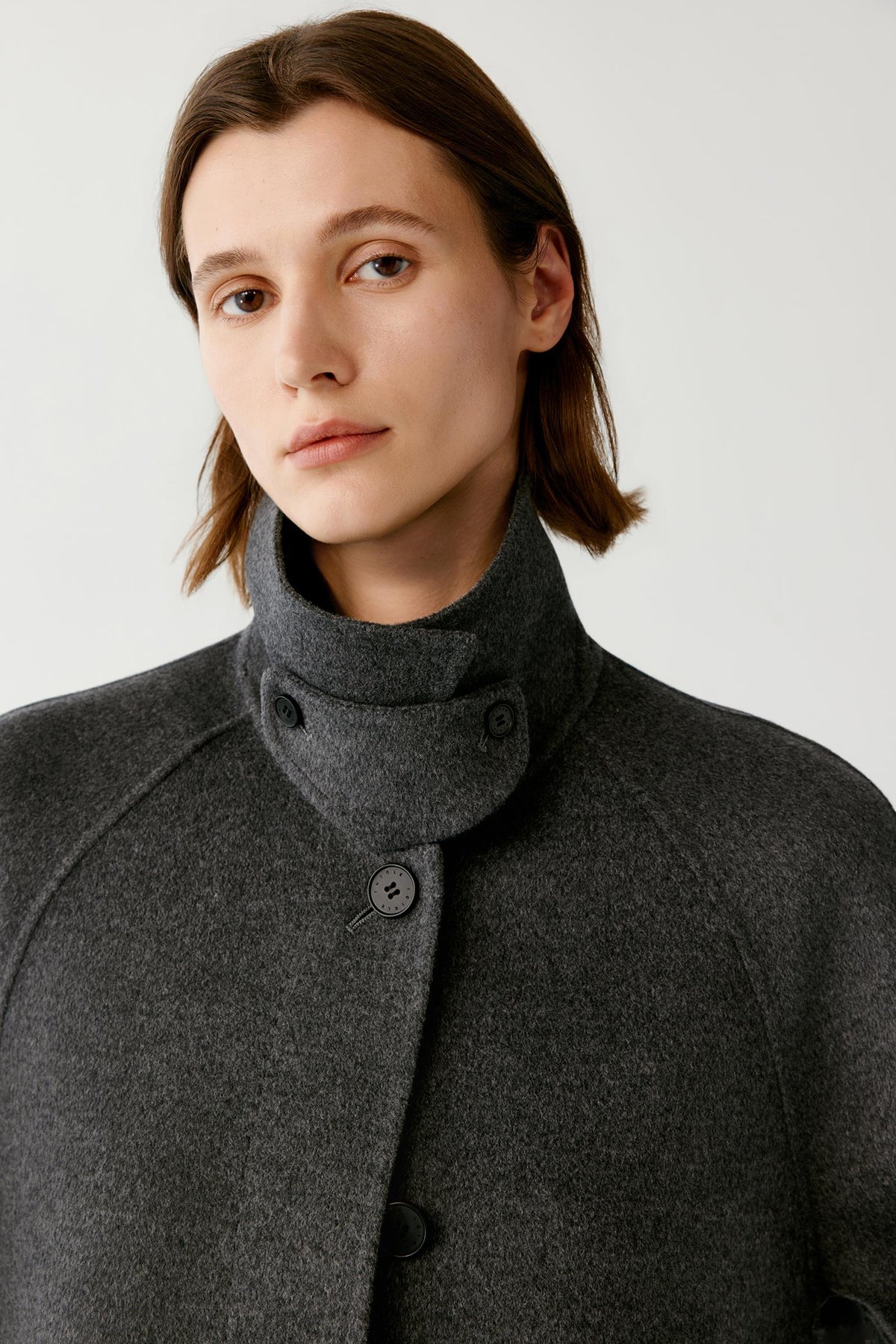 Close-up highlighting the high stand collar and dark grey melange texture of the wool and cashmere coat.