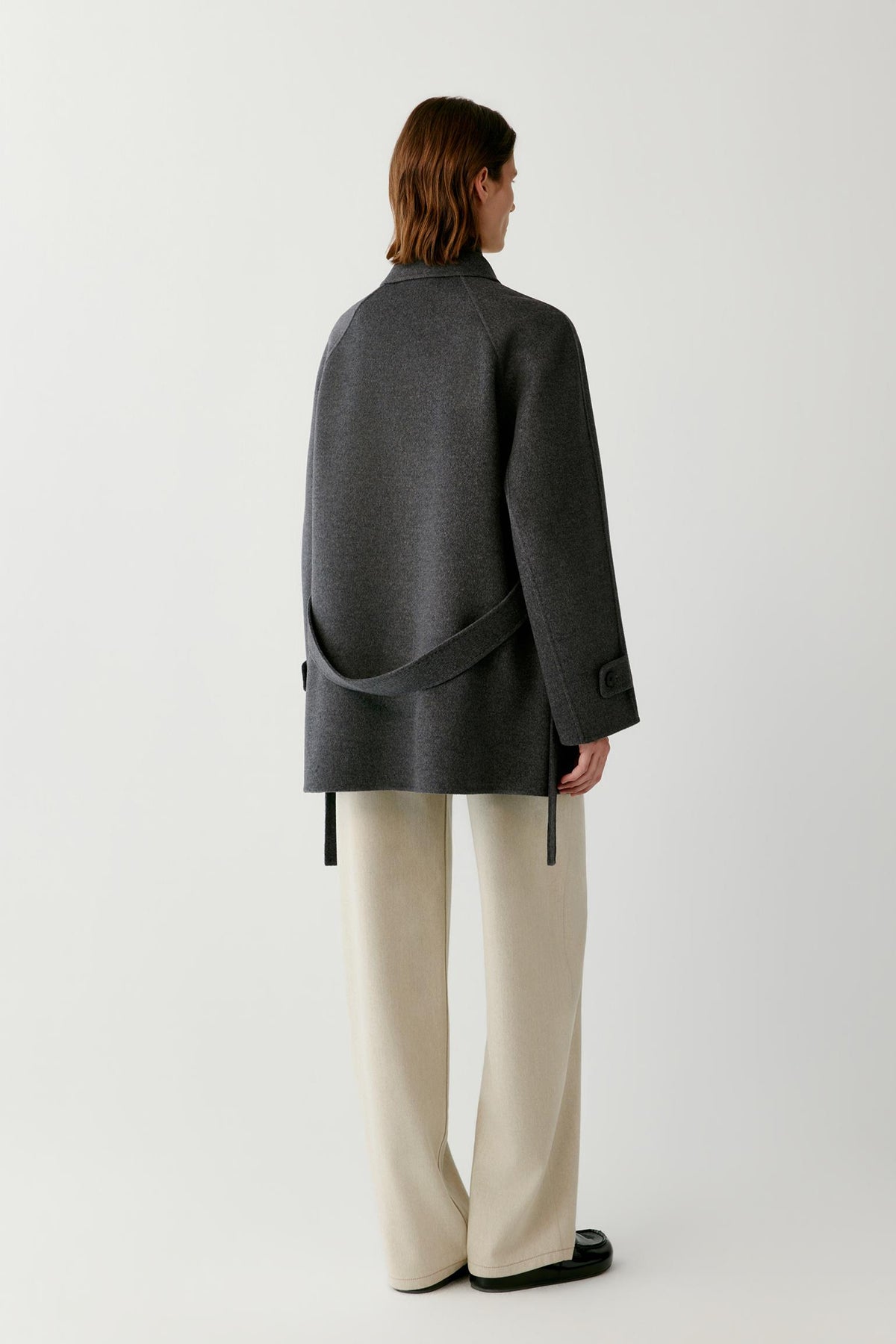 Back view of a woman wearing the dark grey melange wool and cashmere coat, showing the hip-length cut and clean back construction.