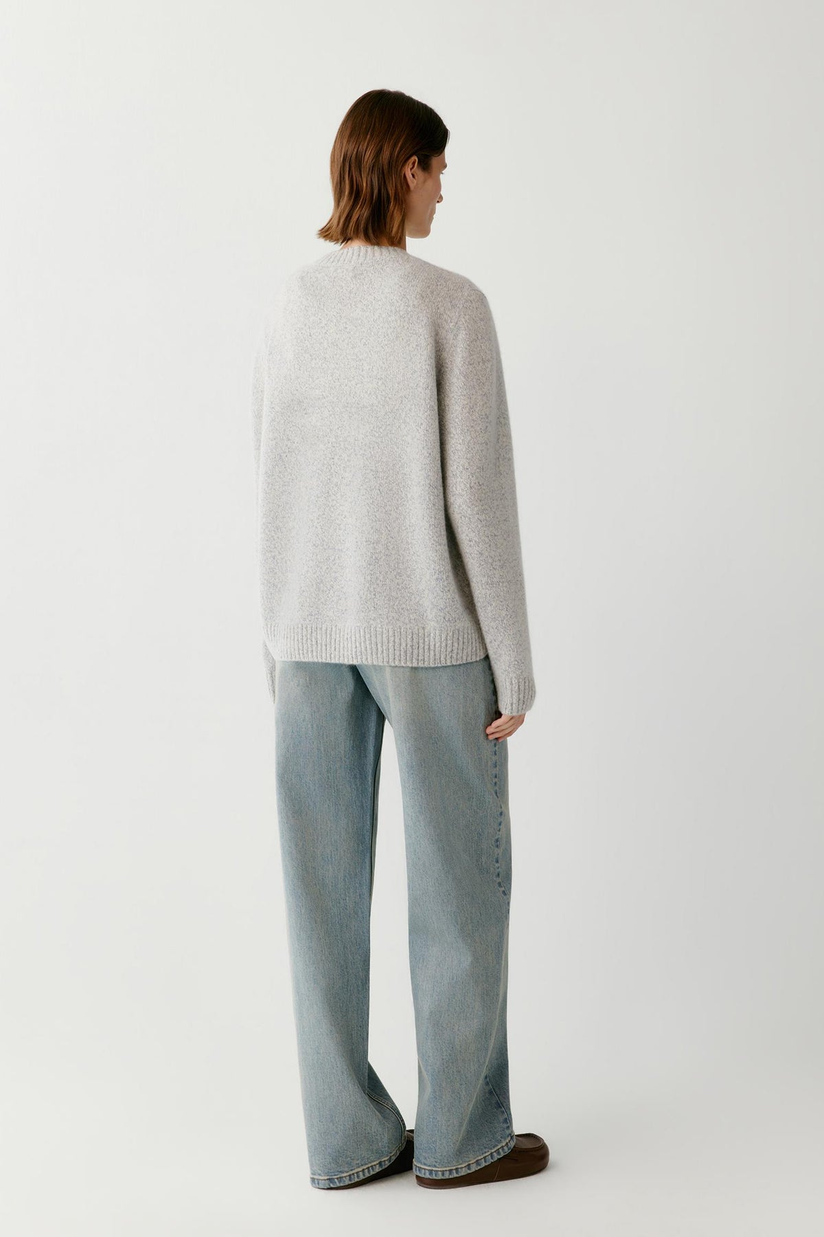 Back view of a woman wearing the blue and white melange cashmere and silk pullover, showing the relaxed silhouette and clean knit construction.