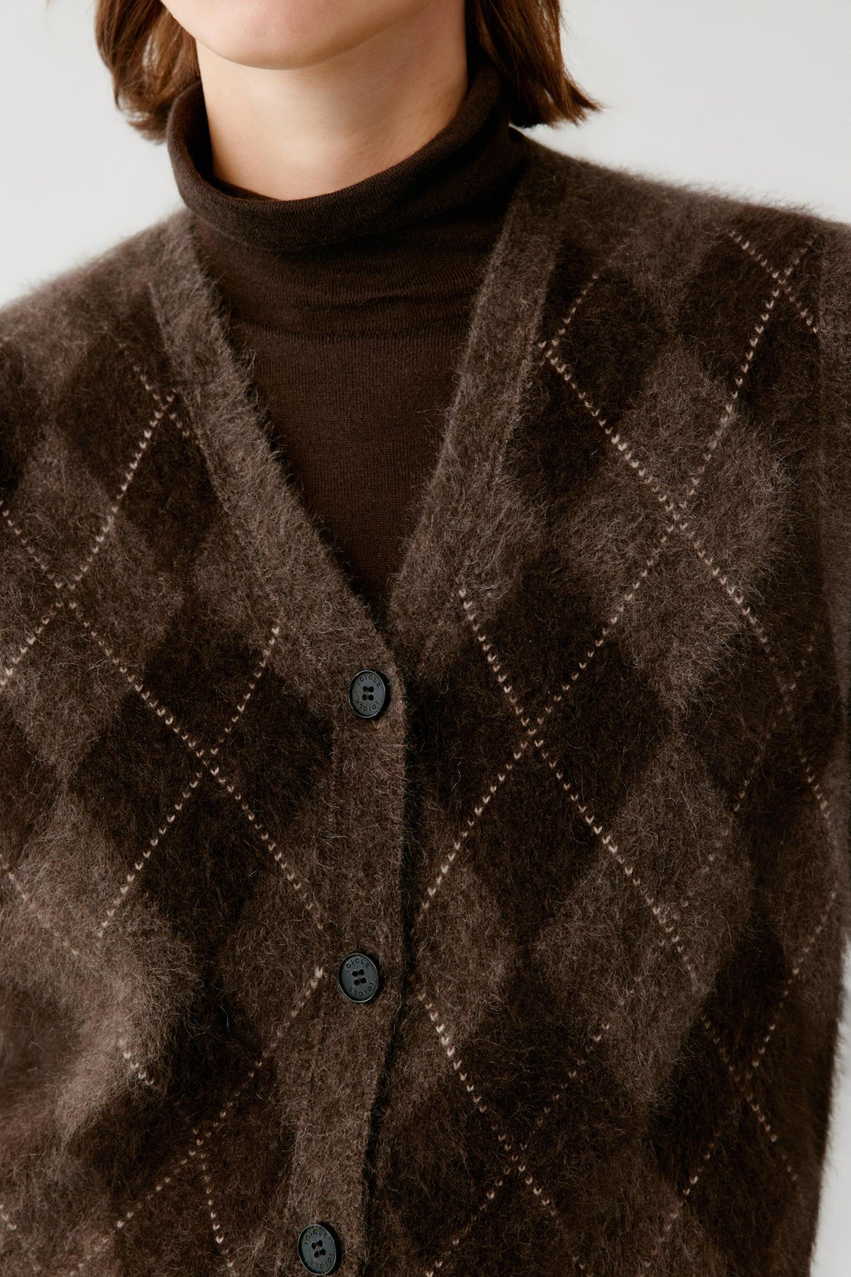 Close-up highlighting the V-neckline, argyle motif and brushed texture of the dark brown yak sleeveless pullover.