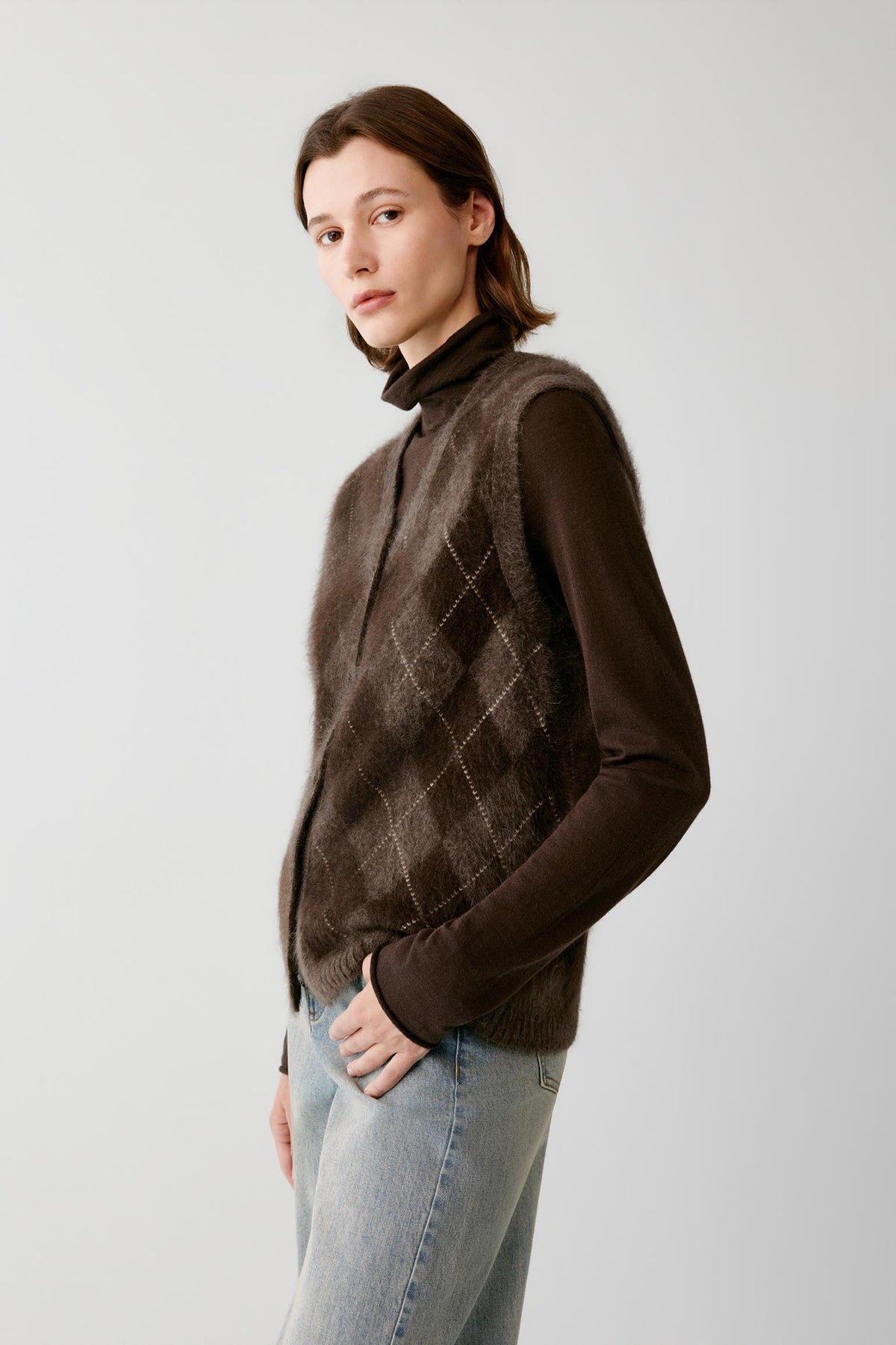 Side view of a woman wearing the dark brown yak sleeveless pullover, highlighting the straight silhouette and brushed knit texture.