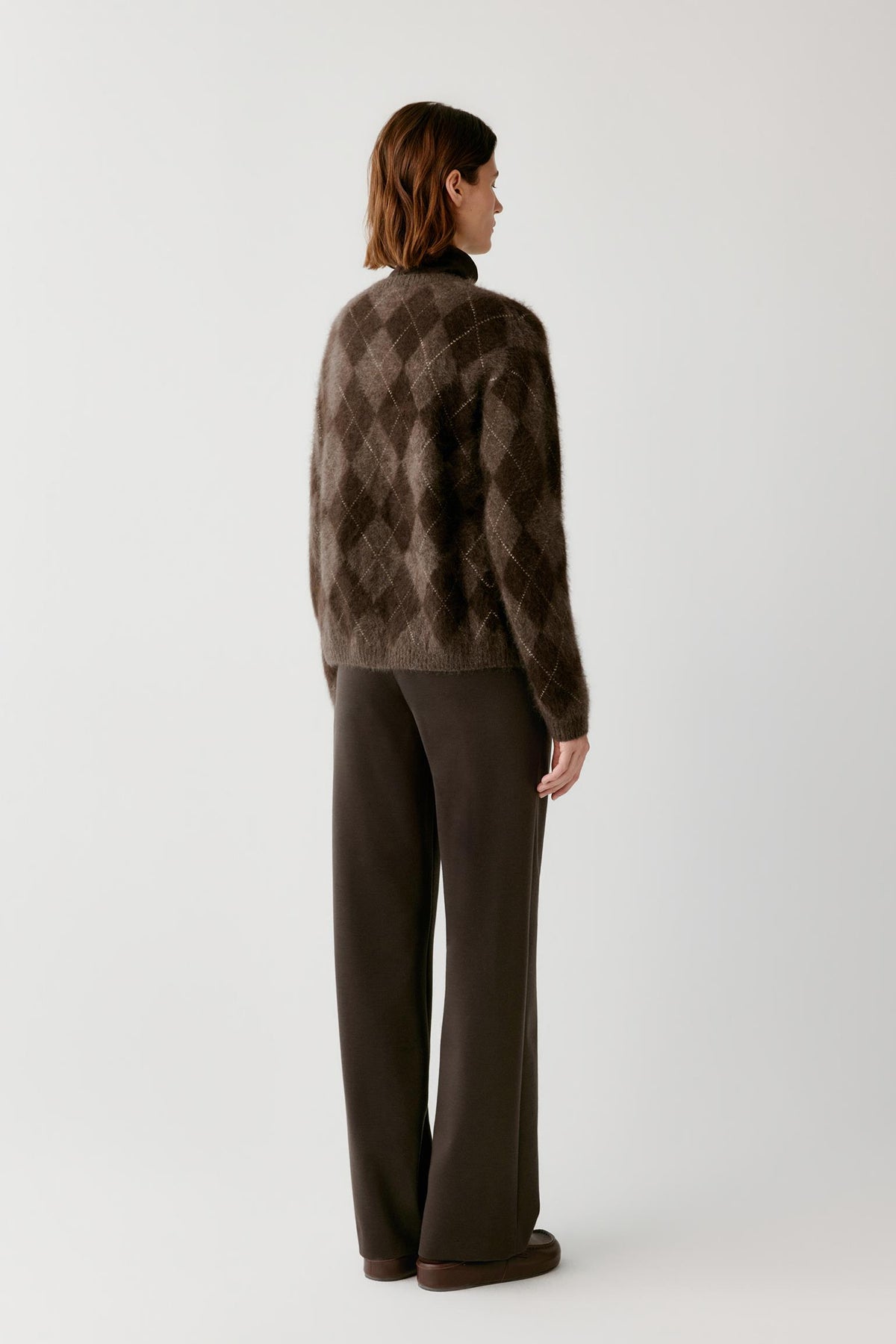 Back view of a woman wearing the dark brown yak cardigan, showing the argyle pattern and straight silhouette.